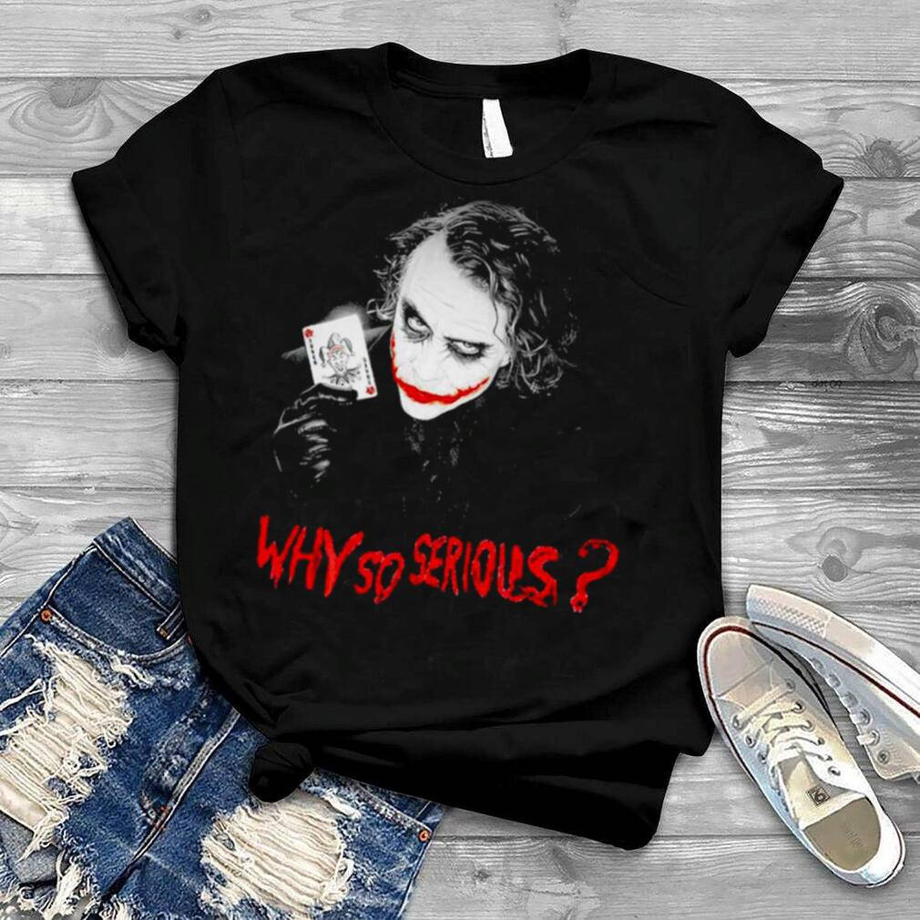 鞋子 桌布 壁紙 — 黑色T恤，印有小丑拿著一張寫有紅色「WHY SO SERIOUS?」字樣的撲克牌，搭配破洞牛仔褲和運動鞋，置於木質表面上。