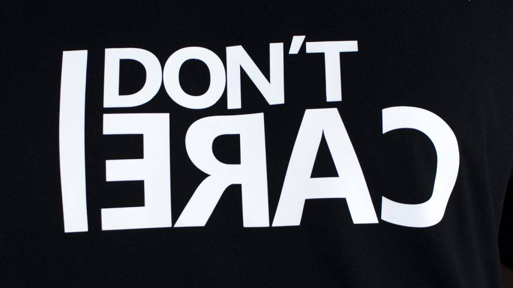 I Dont Care 桌布 壁紙 — 黑色T恤上，白色粗體文字以反向顯示「DON'T CARE」，設計簡潔極簡。
