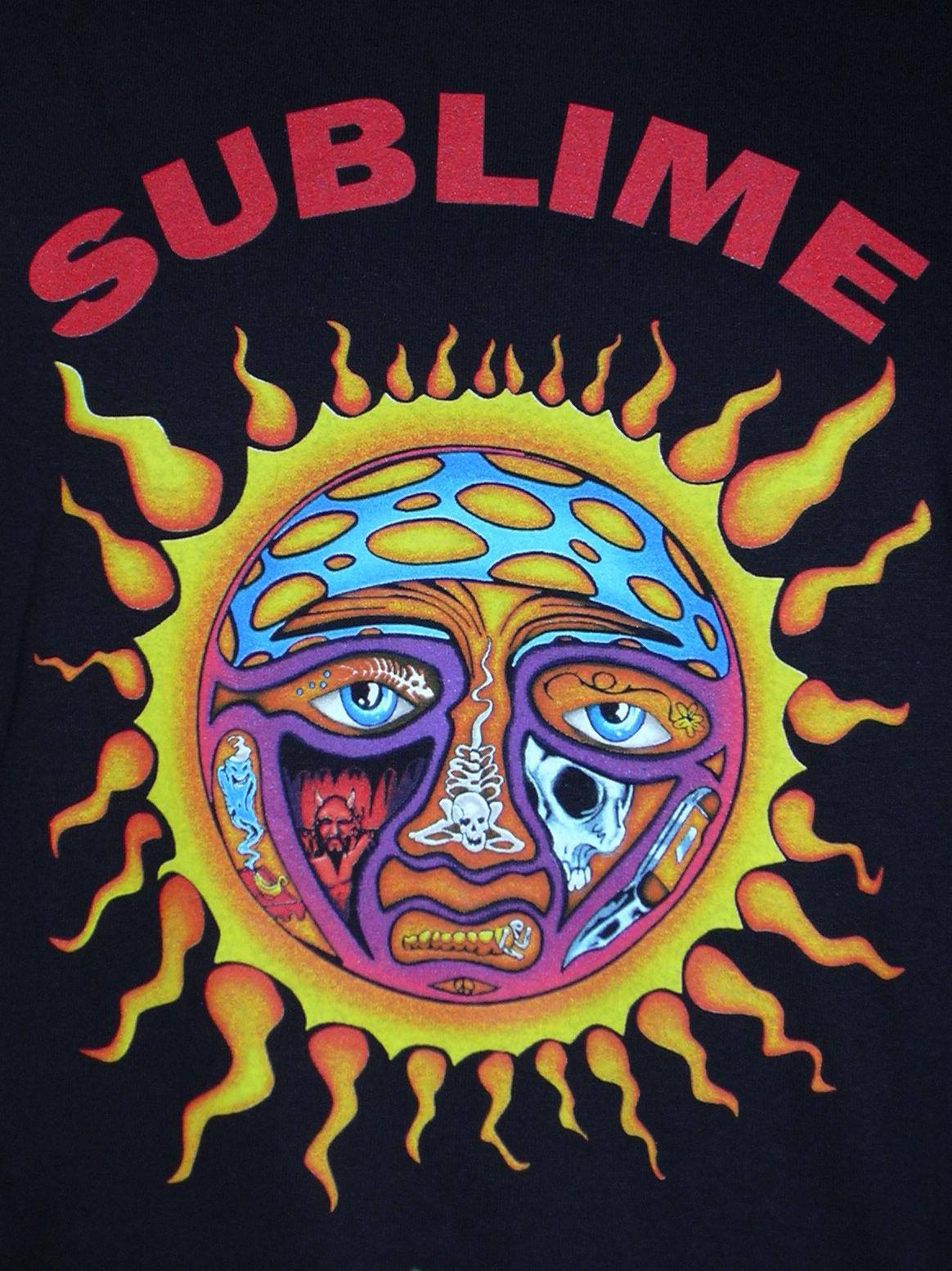 Album Cover 桌布 壁紙 — 黑色T恤上一個迷幻太陽圖案，臉部一分為二，一邊是骷髏頭，另一邊是人類眼睛，周圍環繞著火焰。