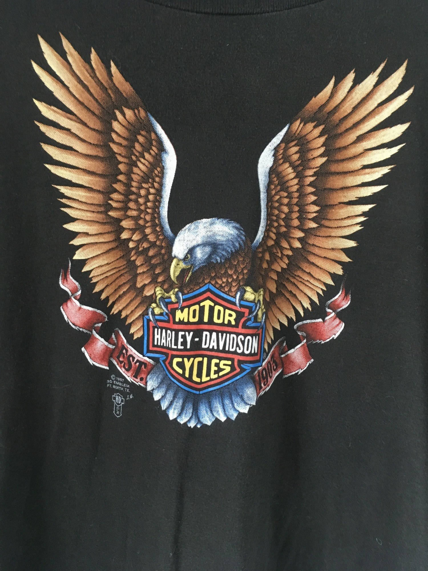 Harley 桌布 壁紙 — 黑色T恤上有一個詳細的圖案，是一隻展翅的白頭鷹抓著哈雷戴維森盾牌標誌。