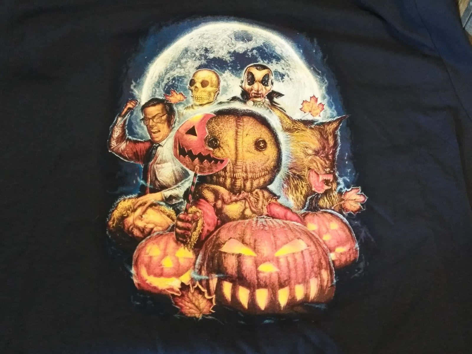 Trick Or Treat 桌布 壁紙 — 黑色T恤上的萬聖節主題圖案展示了一組角色，包括稻草人、南瓜燈、狼人和頭骨，背景是滿月。