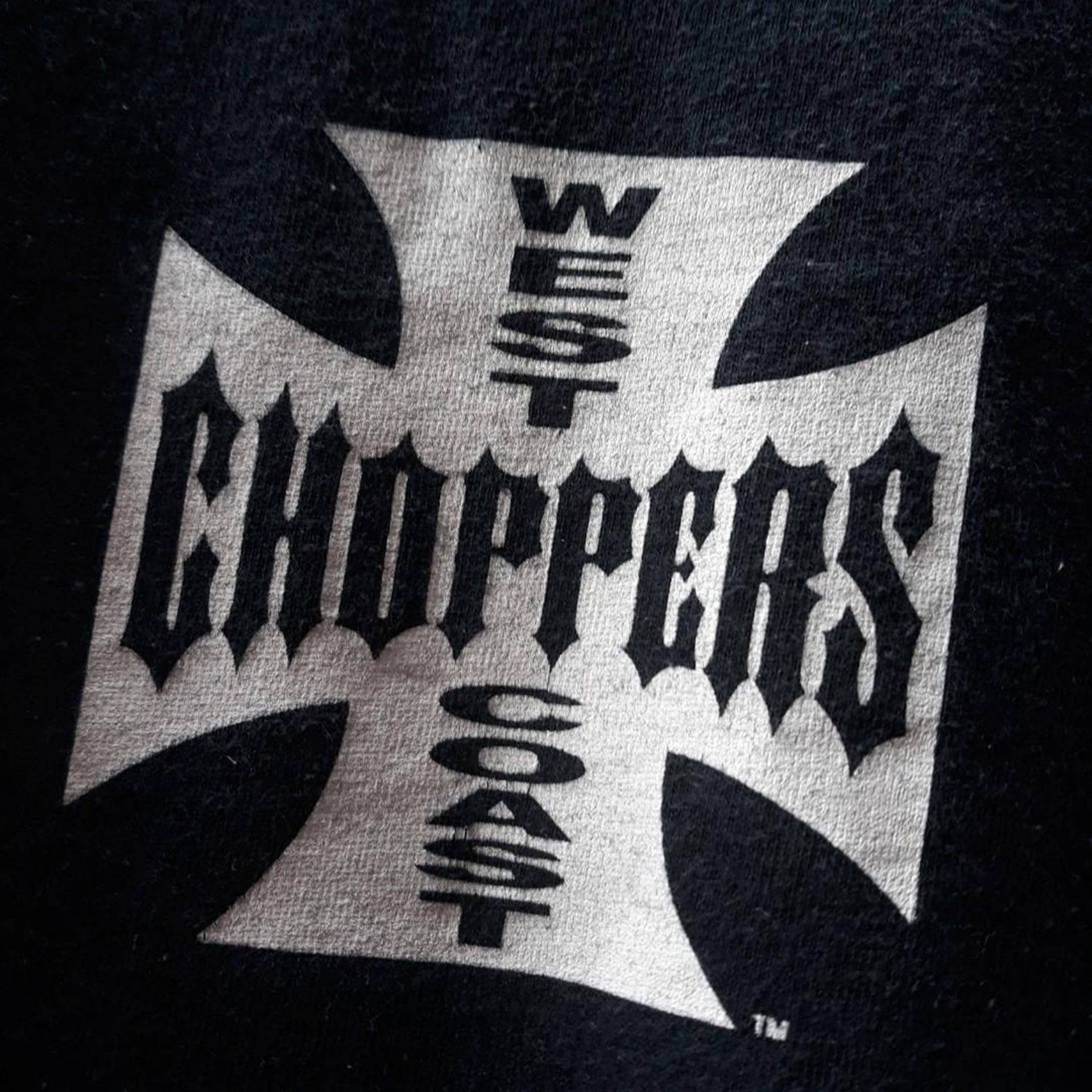 Choppers 桌布 壁紙 — 黑色T恤特寫，帶有銀色鐵十字標誌和粗體黑色文字「WEST CHOPPERS COAST」。