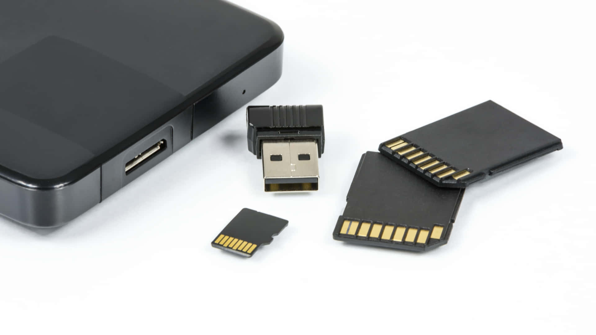 Backup 桌布 壁紙 — 黑色USB隨身碟和記憶卡整齊排列在智慧型手機旁邊，置於潔白表面上。