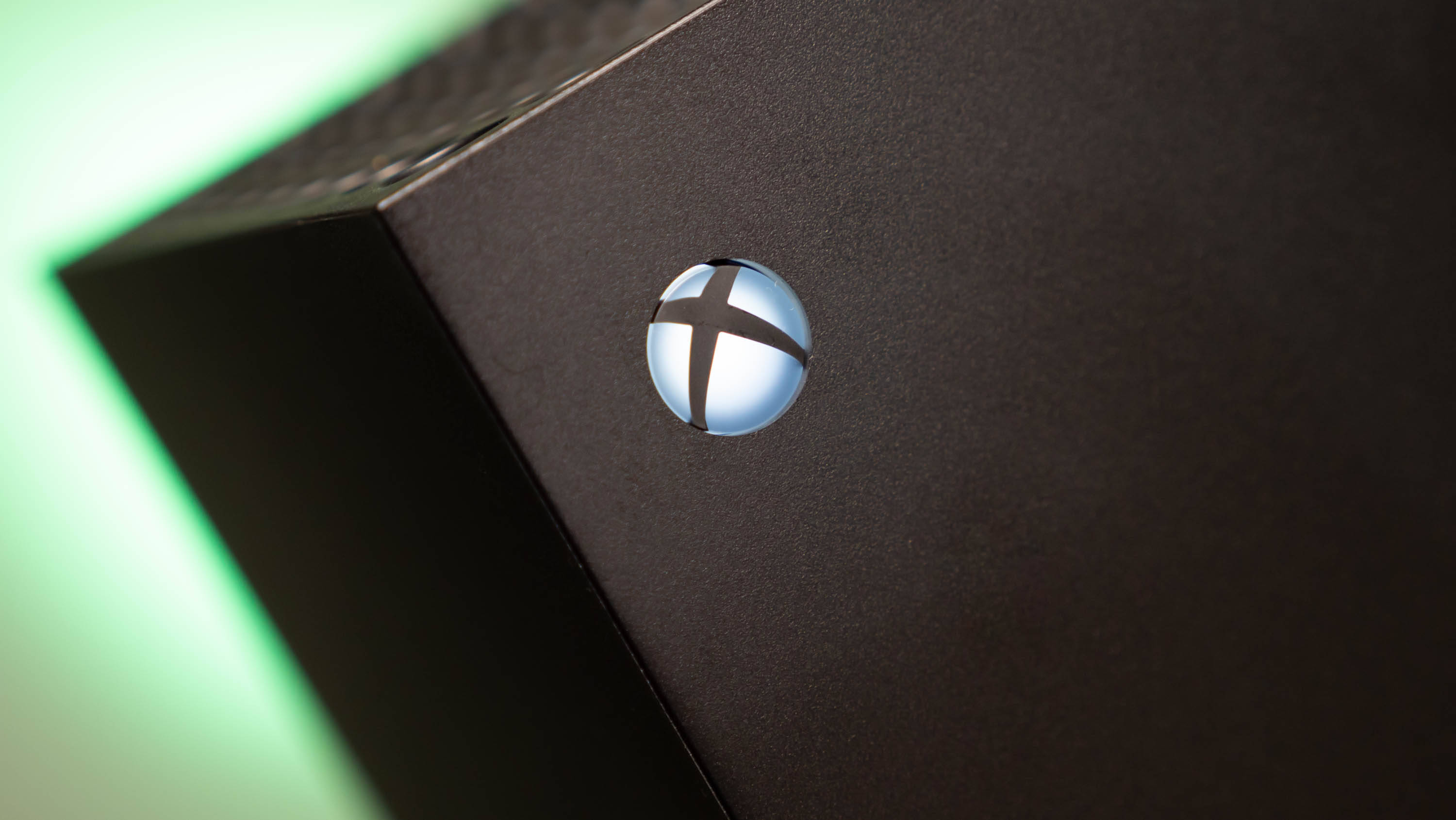 X 桌布 壁紙 — 黑色Xbox主機特寫，帶有發光的綠色環境光和發亮的標誌。