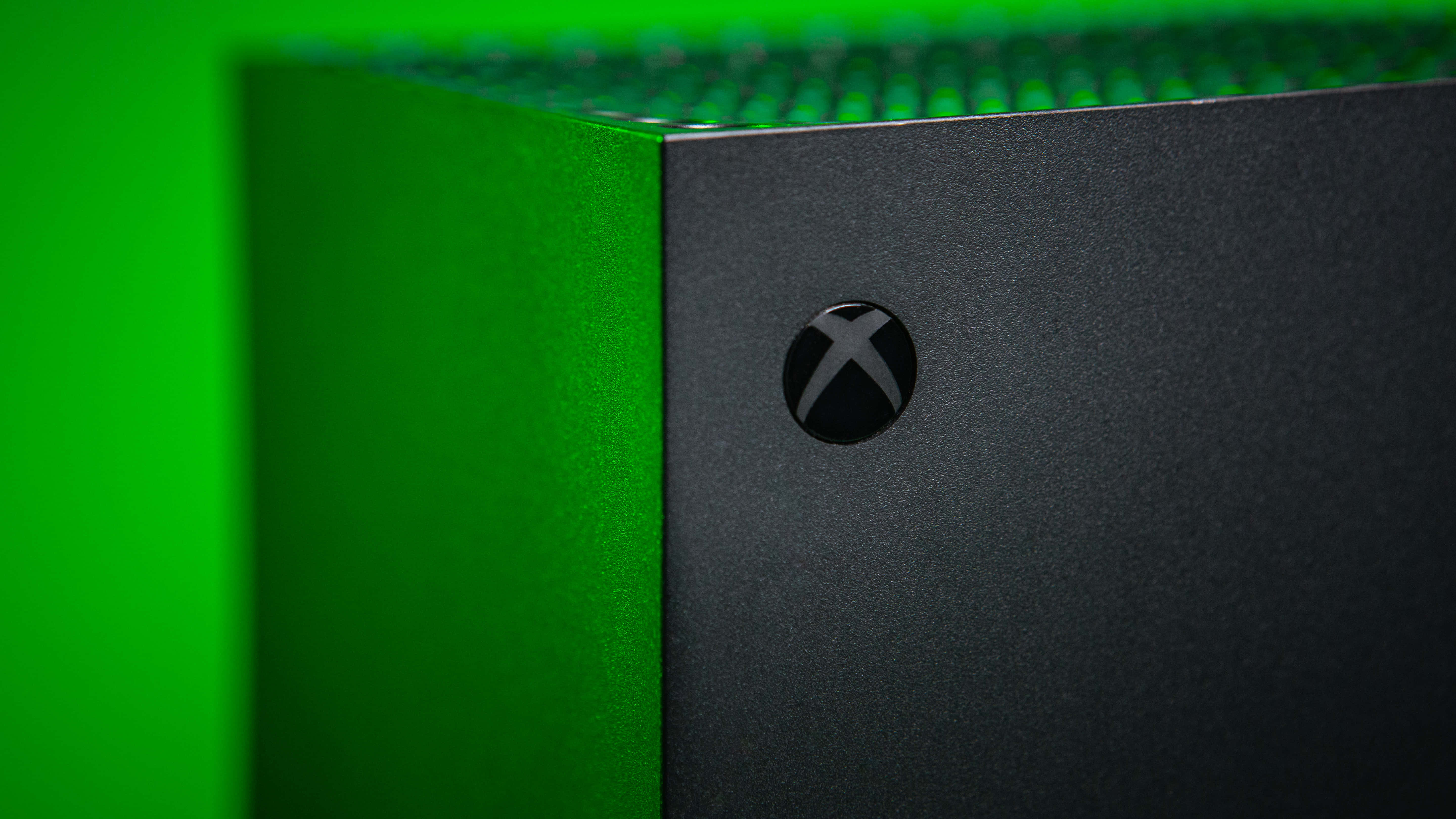 Gaming Consoles 桌布 壁紙 — 黑色Xbox主機特寫，帶有發光綠色點綴和紋理表面。