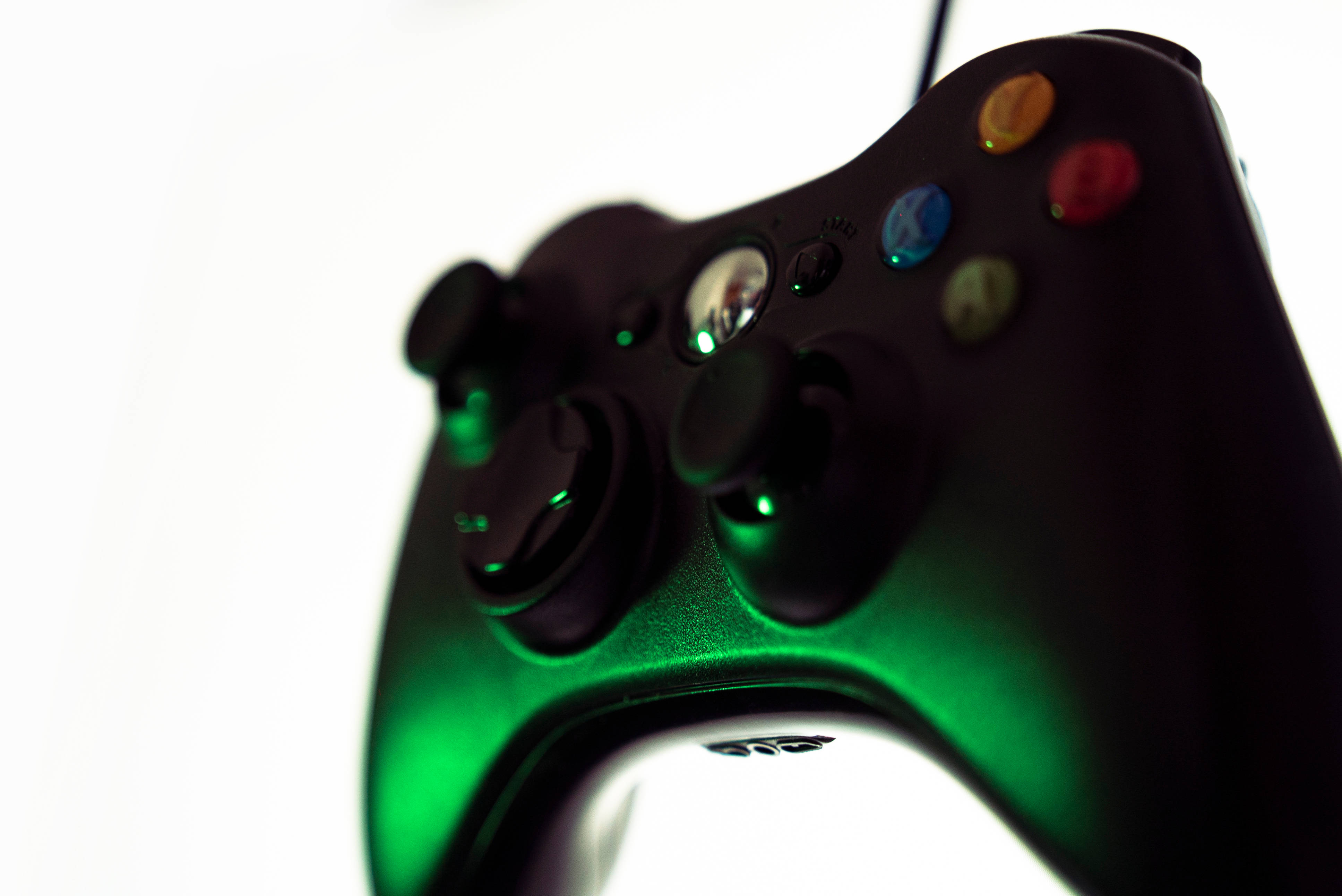 Joystick 桌布 壁紙 — 黑色Xbox手把在純白背景上發出鮮豔綠光的特寫。