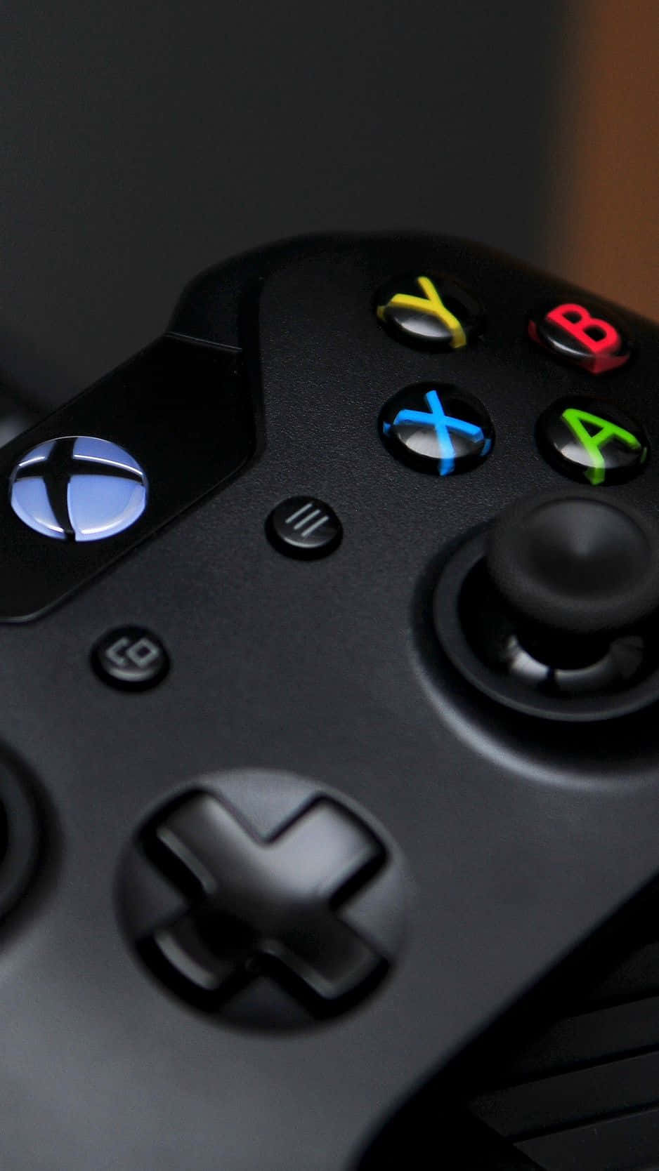遊戲 桌布 壁紙 — 黑色Xbox手把特寫，帶有發光彩色按鈕和發光標誌，背景為深色。