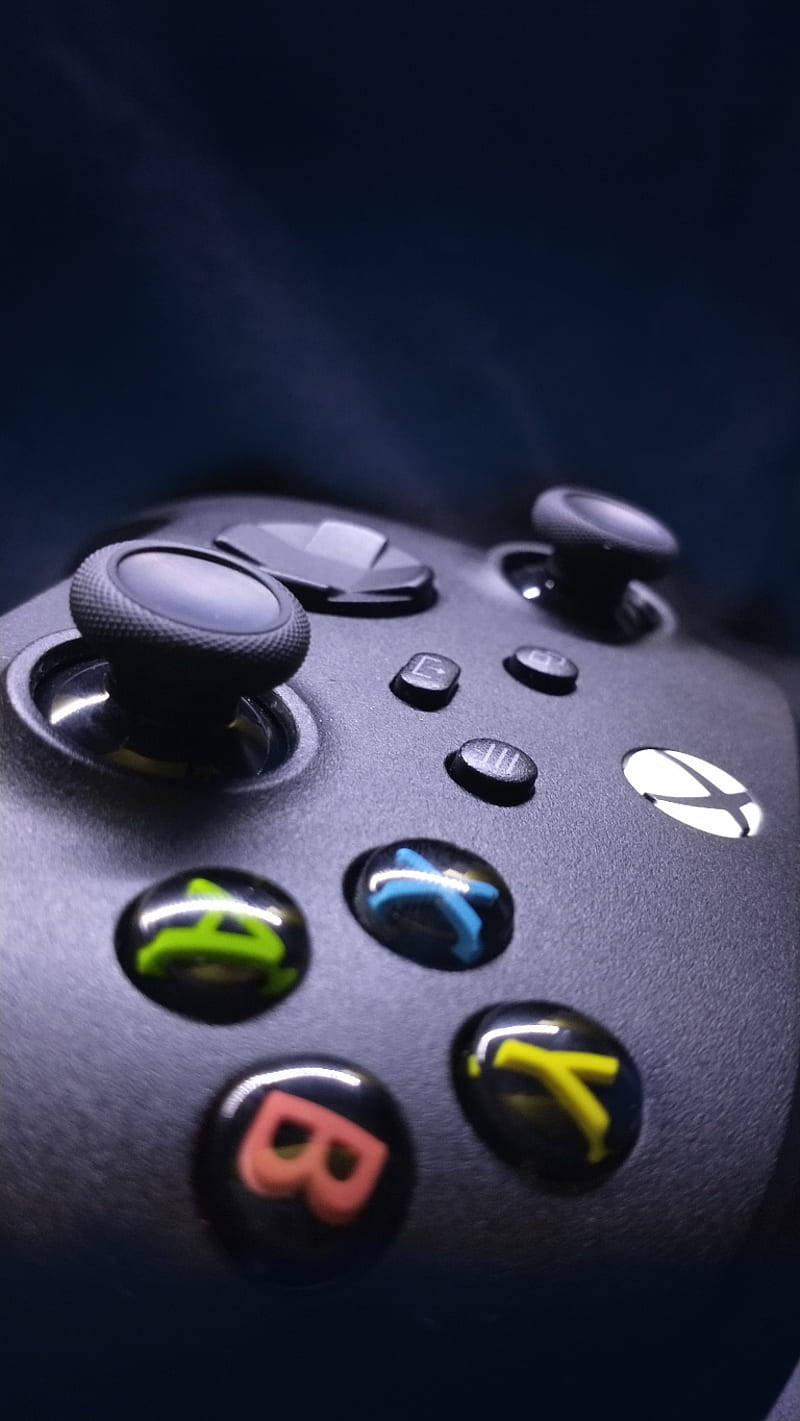 X 桌布 壁紙 — 黑色Xbox手把的特寫，帶有發光的彩色按鈕，背景為深色。