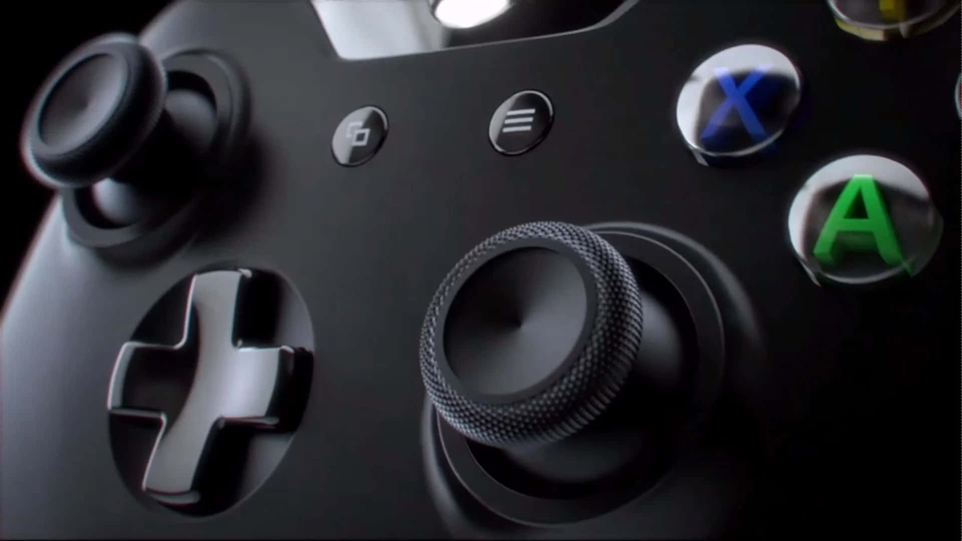 桌布 壁紙 — 黑色Xbox控制器的特寫，突出紋理握把和發光彩色按鈕，背景為深色。