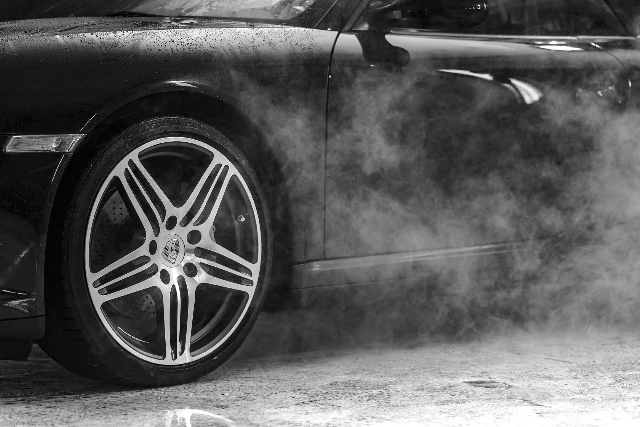Wash 桌布 壁紙 — 黑色保時捷跑車的車輪在單色濕滑路面上甩尾時揚起煙霧。