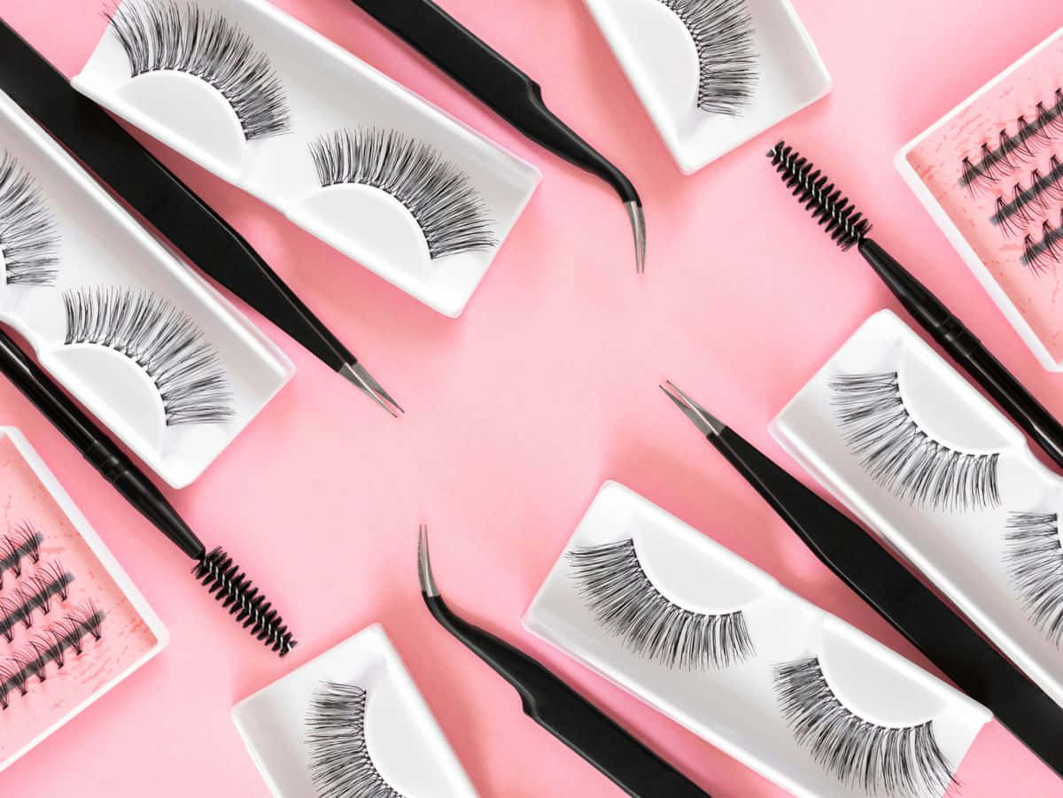 Eyelash 桌布 壁紙 — 黑色假睫毛和鑷子排列在柔軟的粉紅色背景上，採用平鋪構圖。