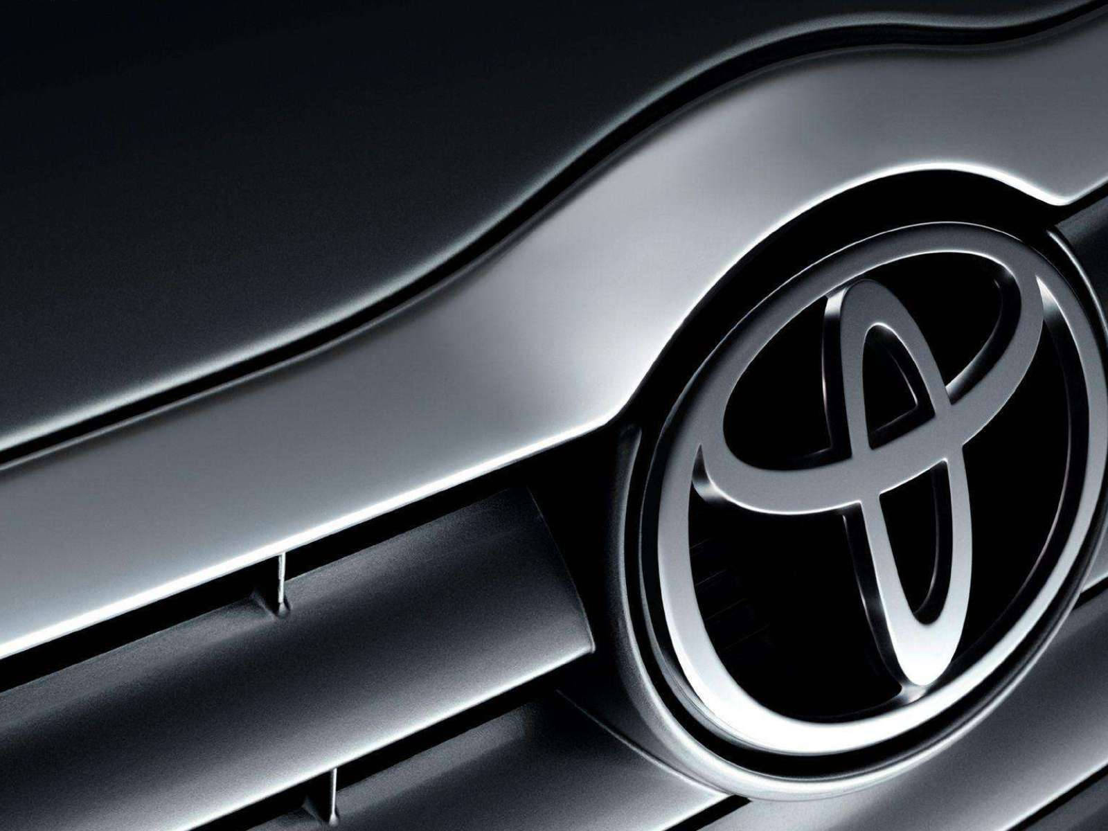 Toyota 桌布 壁紙 — 黑色光面汽車格柵上帶有銳利反射的時尚銀色豐田標誌特寫。