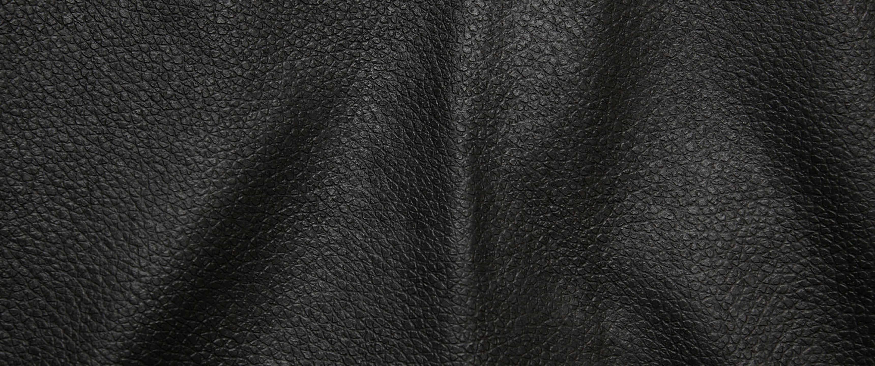texture 桌布 壁紙 — 黑色卵石紋皮革的微距特寫，在柔和光線下呈現自然褶皺和粒面質感。