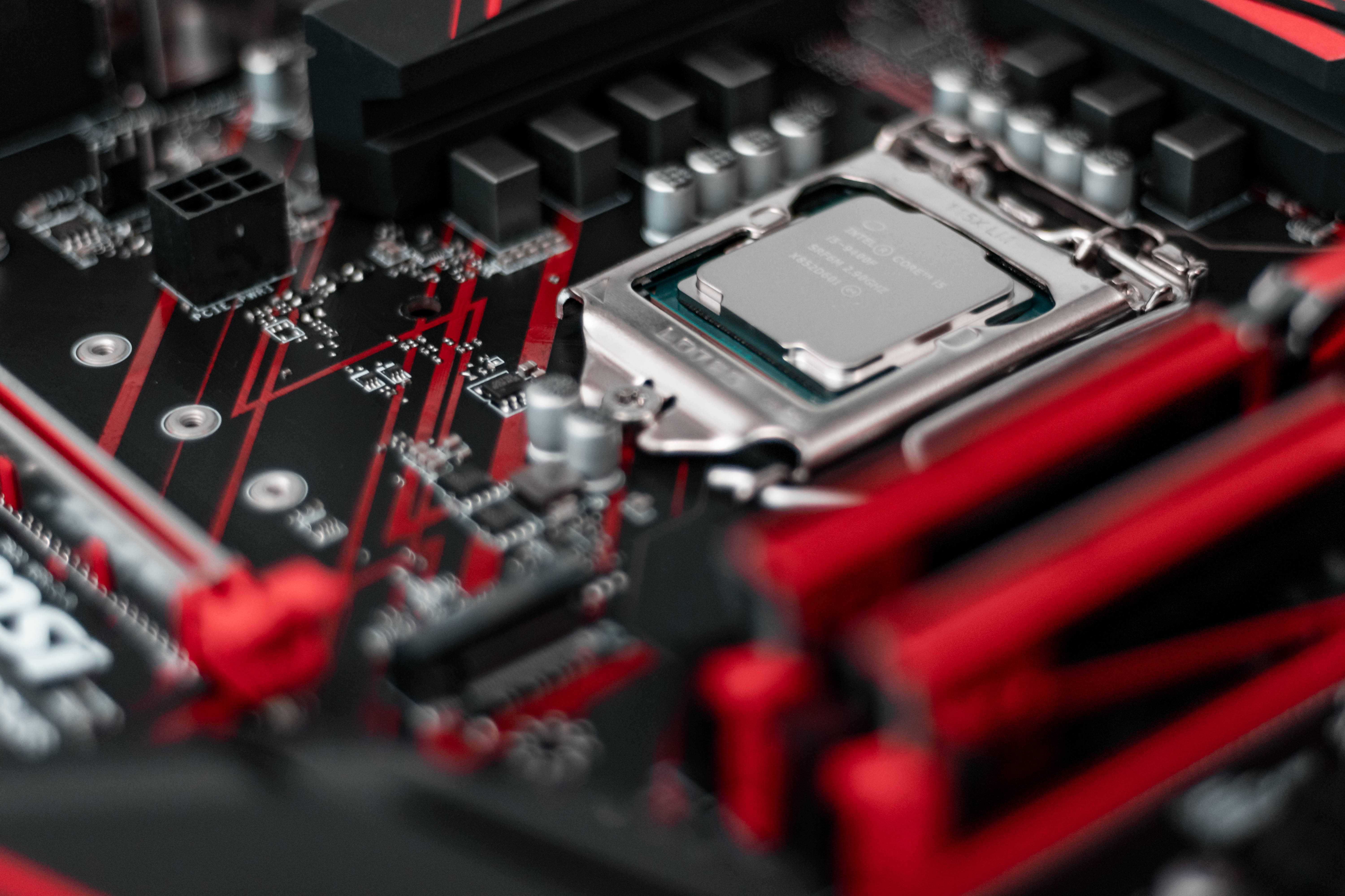 msi 2560x1080 桌布 壁紙 — 黑色和紅色電腦主機板的特寫，帶有銀色 CPU 插槽和模糊的組件。