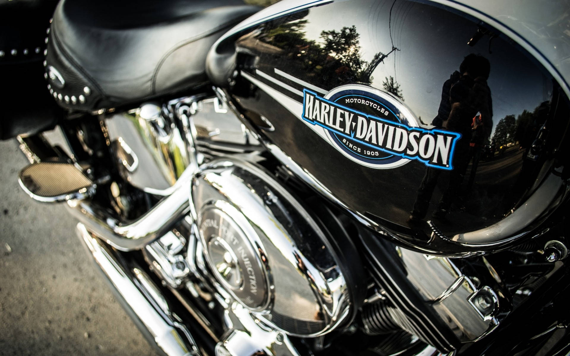 Harley 桌布 壁紙 — 黑色哈雷戴維森機車近距離特寫，鍍鉻飾件反射出人物和樹木。