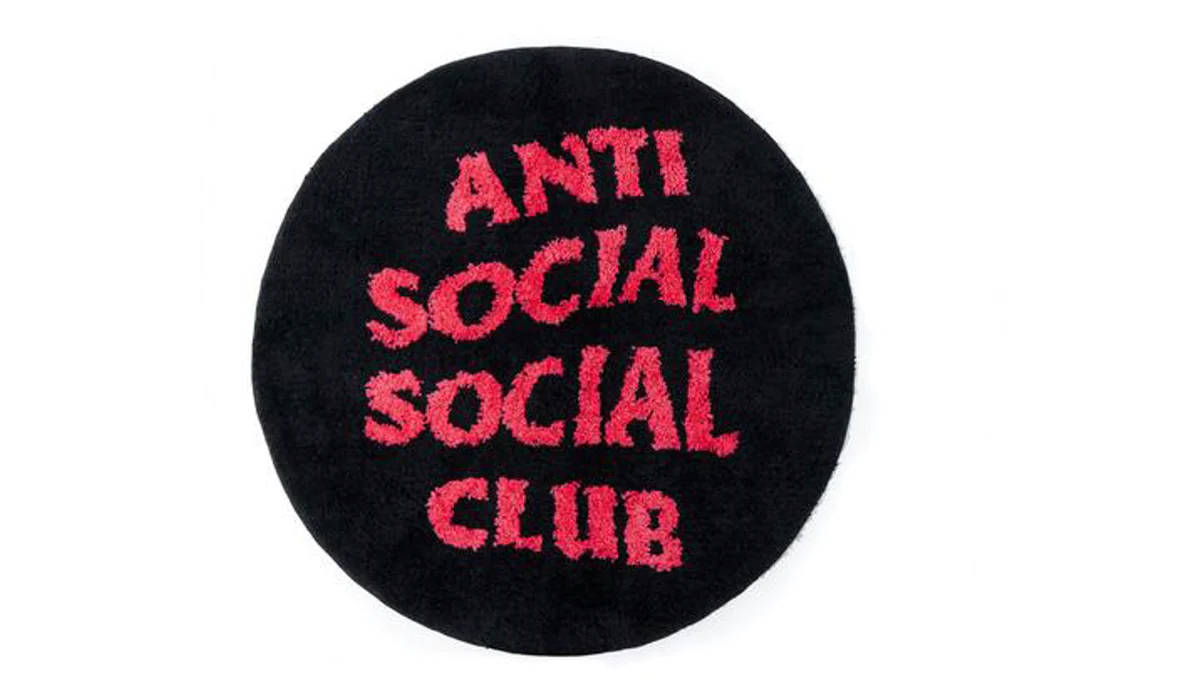 club 桌布 壁紙 — 黑色圓形地毯，上面有粉紅色粗體刺繡文字「ANTI SOCIAL SOCIAL CLUB」，背景為白色。