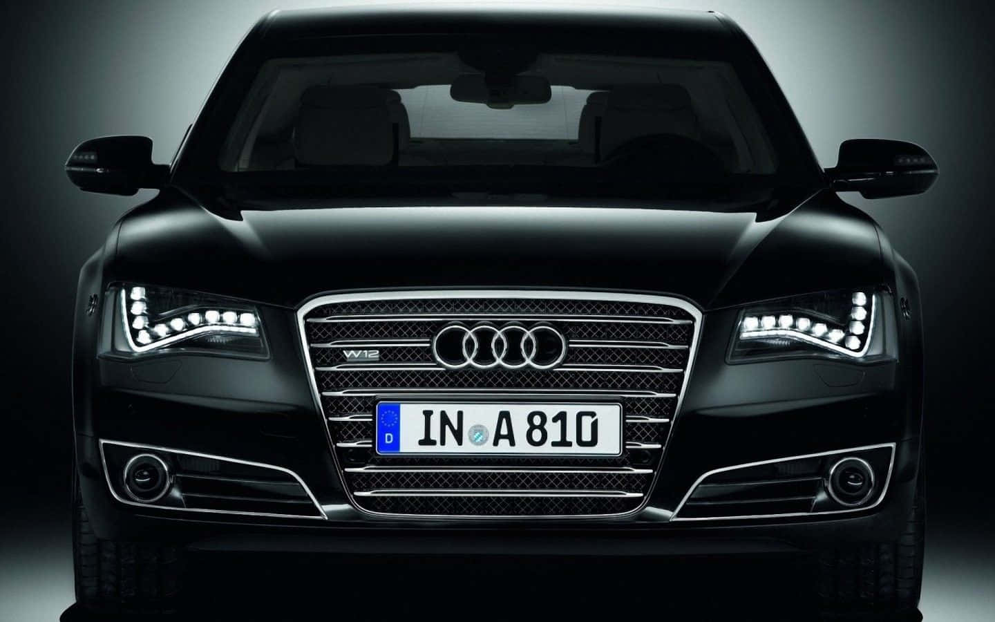 Audi S8 桌布 壁紙 — 黑色奧迪A8豪華轎車的正面視圖，配備發光LED頭燈和鍍鉻飾邊，背景為深色攝影棚。