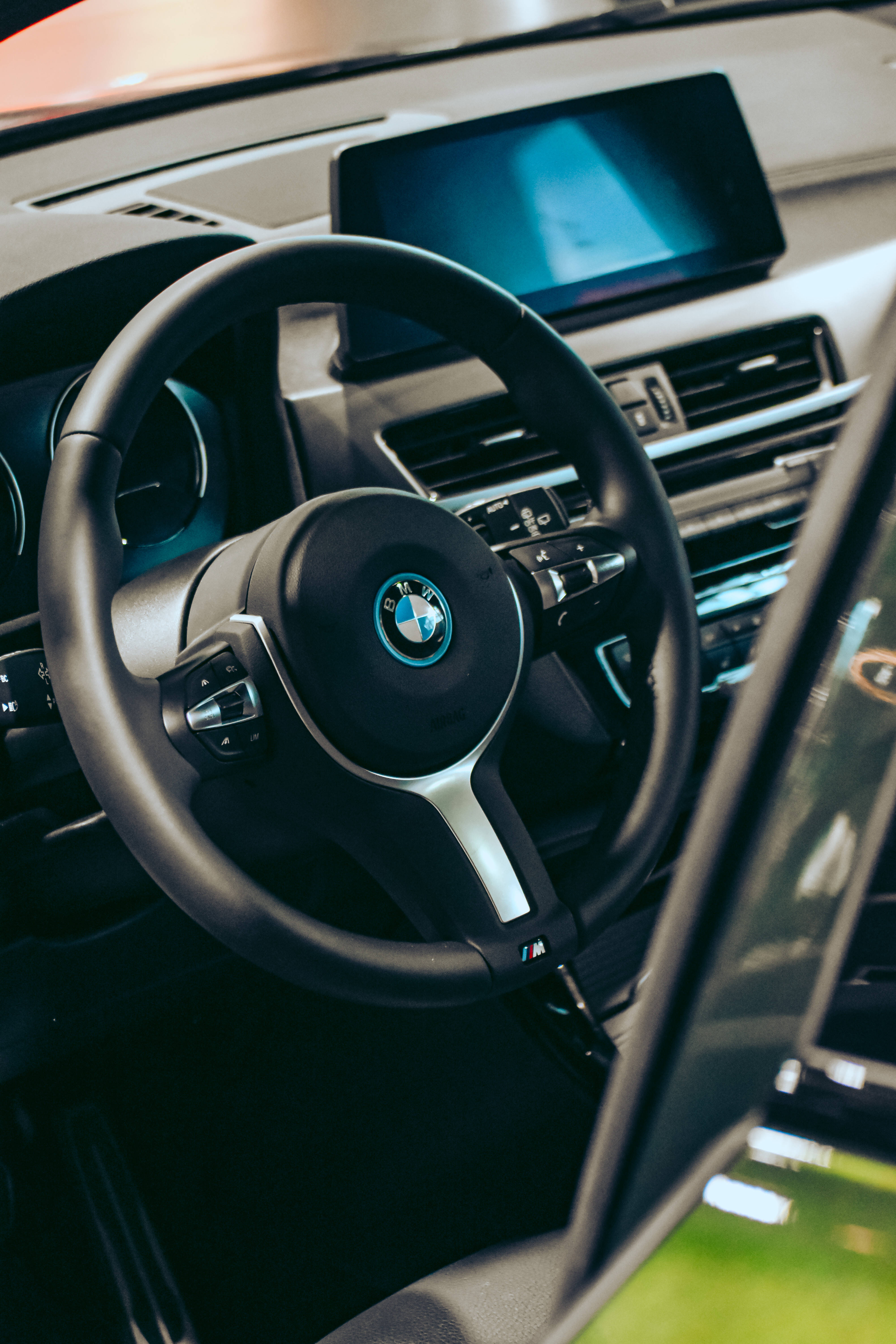 Black Bmw 桌布 壁紙 — 黑色寶馬M系列方向盤特寫，帶有發光藍色裝飾和數位儀表板。