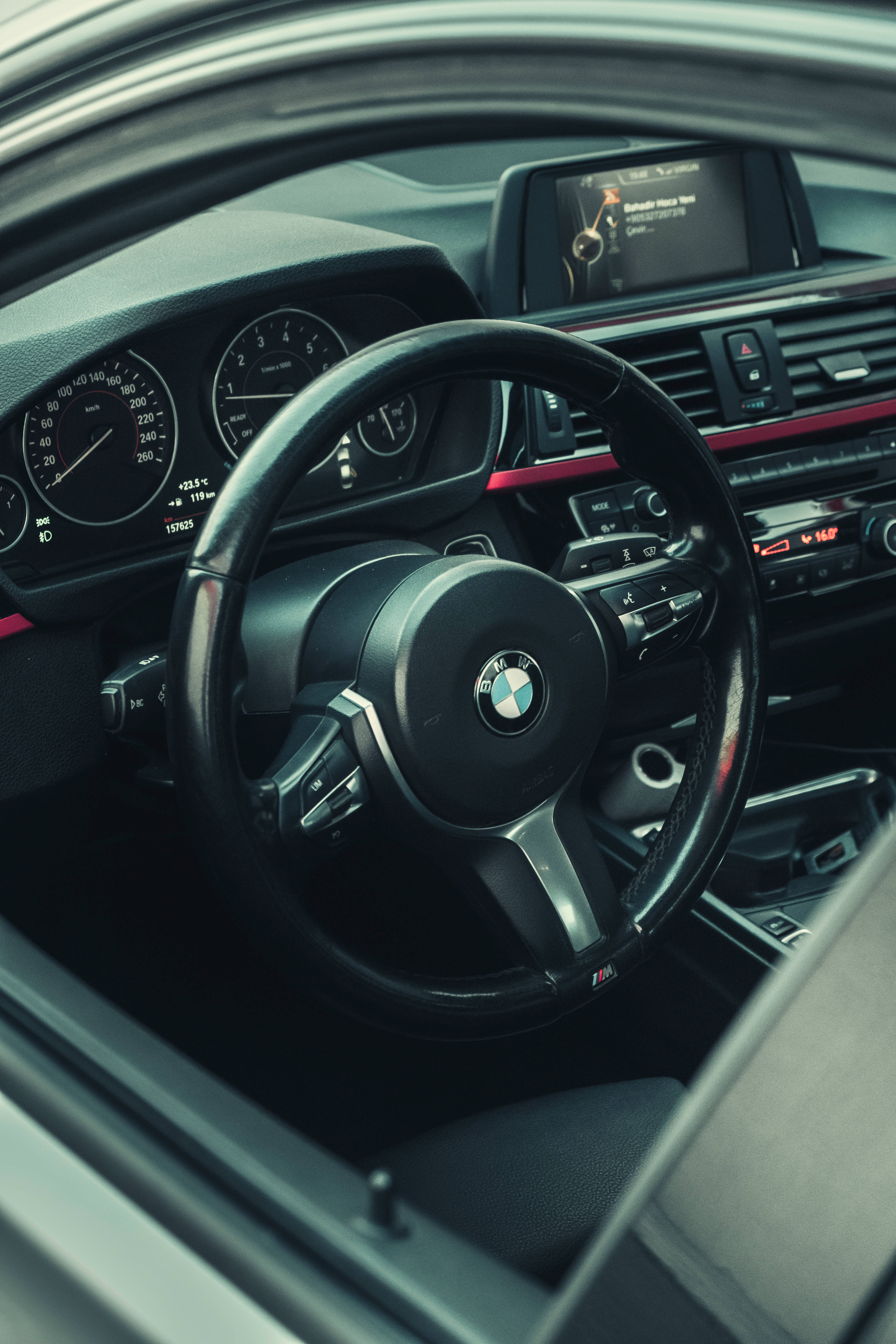 Black Bmw 桌布 壁紙 — 黑色寶馬汽車內飾的近距離視圖，帶有紅色點綴和數位儀表板顯示屏。