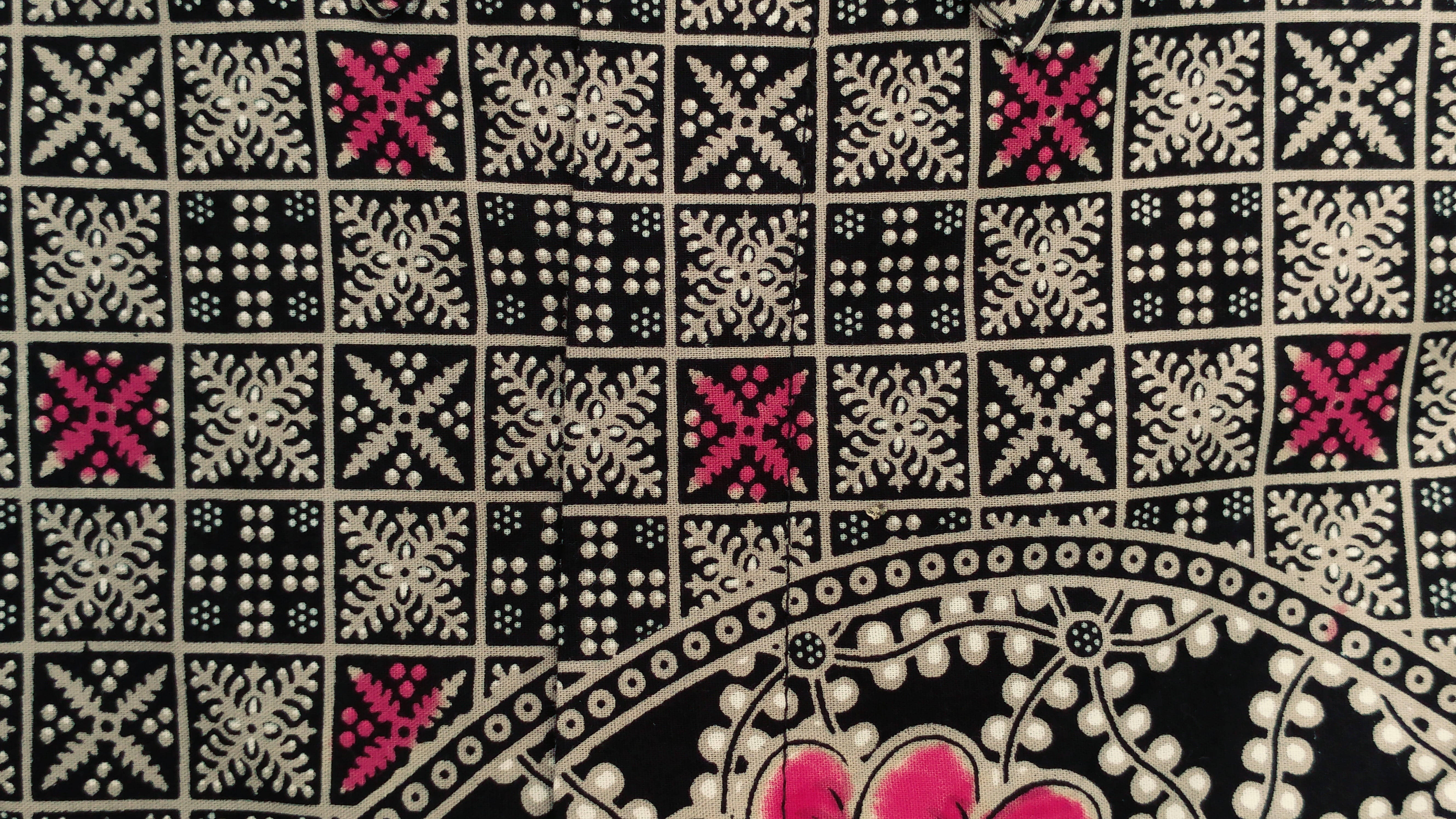 Geometric 桌布 壁紙 — 黑色布料特寫，帶有複雜的白色和粉紅色刺繡幾何圖案，以重複網格排列。