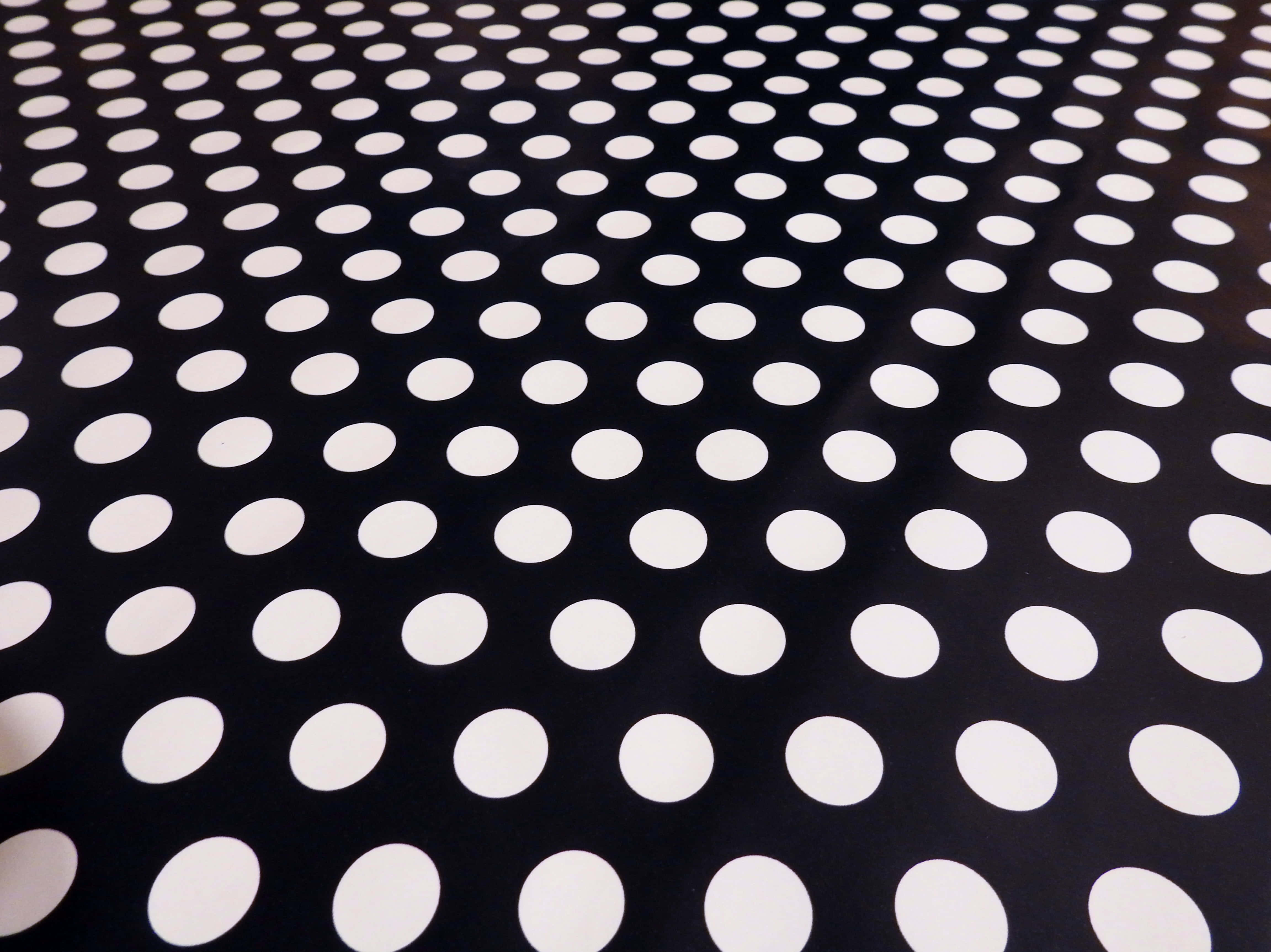 Black And White Dots 桌布 壁紙 — 黑色布料的特寫，上面有均勻分佈的白色圓點，形成大膽的幾何圖案。