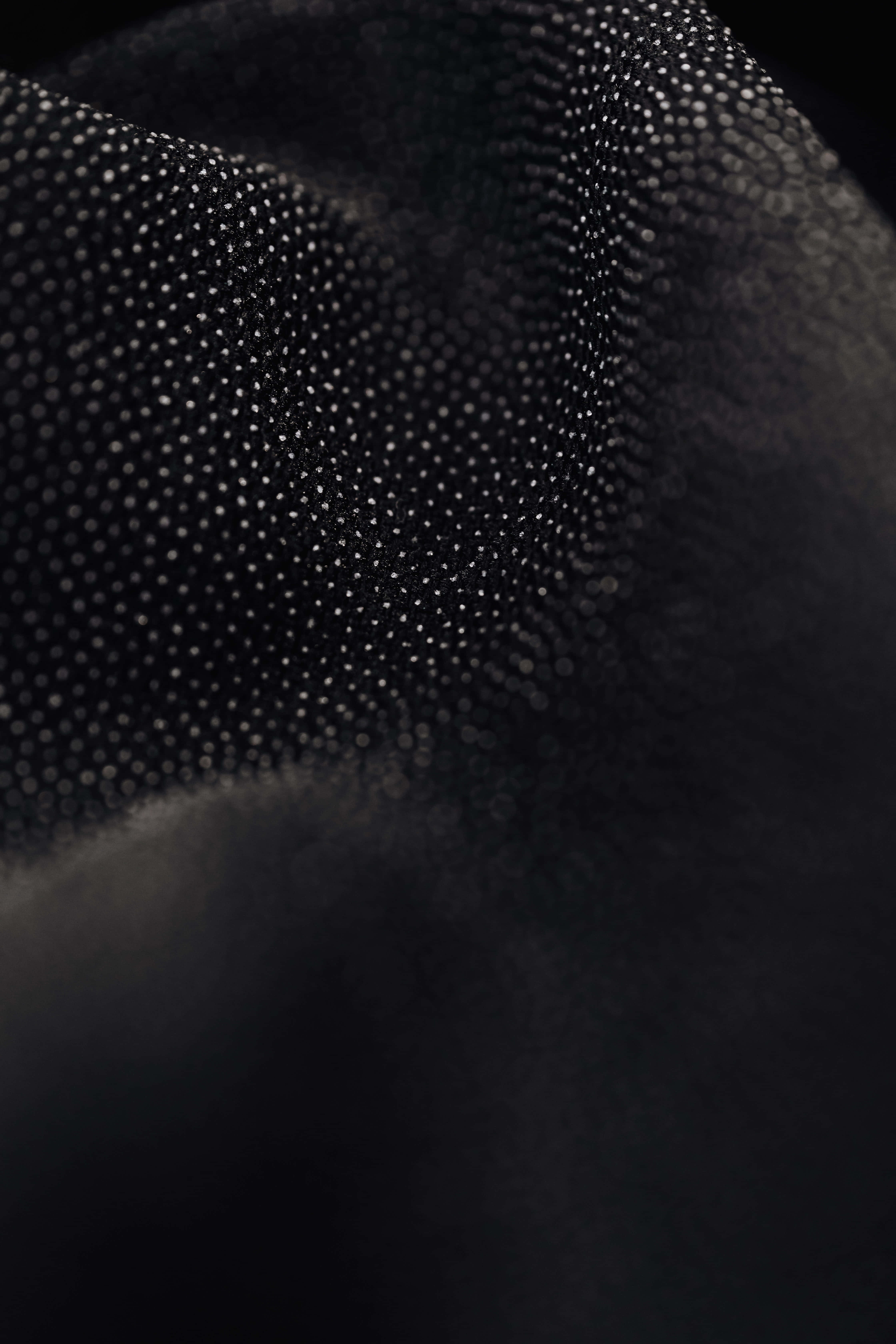 Black And White Dots 桌布 壁紙 — 黑色布料的特寫，帶有圓點紋理，柔和的光線突顯其複雜圖案和深度。