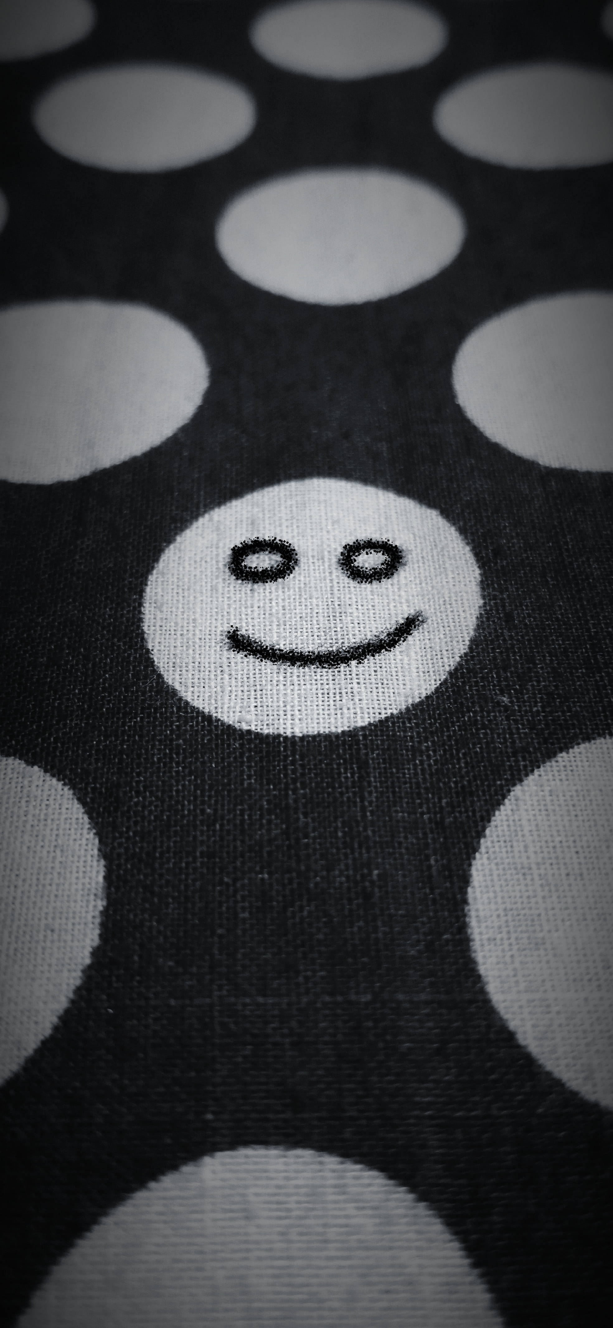 Black Emoji 桌布 壁紙 — 黑色布料近距離特寫，帶有白色圓點和中央笑臉圖案。