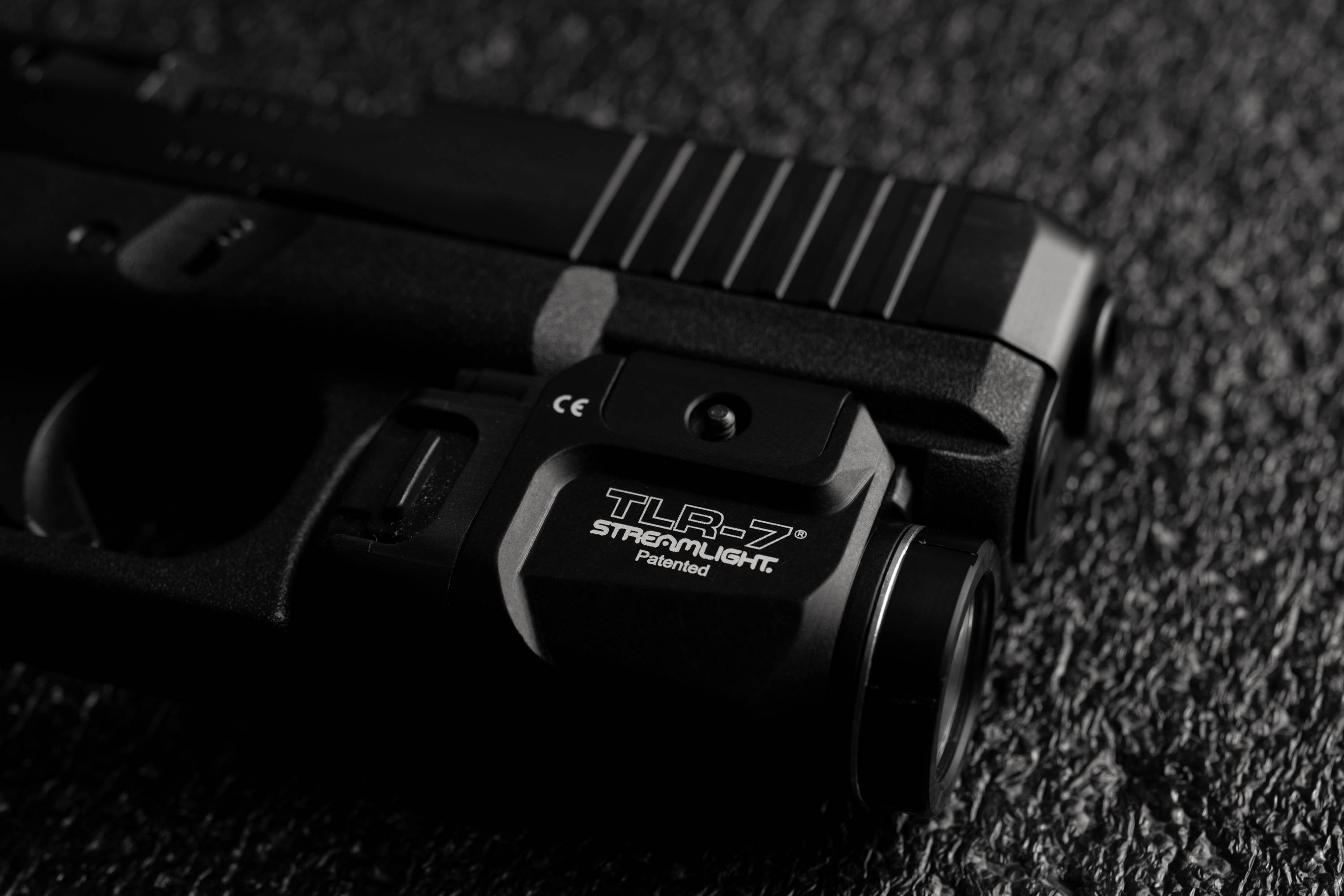 Glock 桌布 壁紙 — 黑色手槍特寫，配備 Streamlight TLR-7 雷射瞄準器，放置在紋理深色表面上。