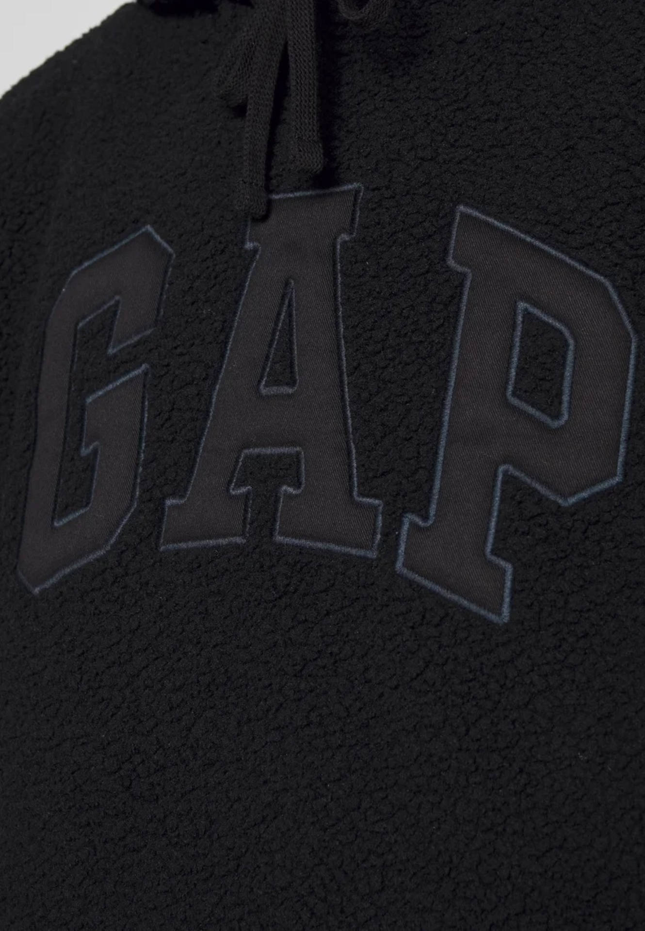 Gap 桌布 壁紙 — 黑色抓絨連帽衫特寫，帶有粗體刺繡GAP標誌和抽繩。