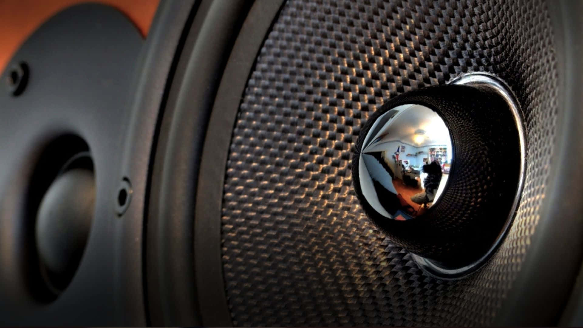 Car Audio 桌布 壁紙 — 黑色揚聲器格柵的特寫，帶有反射性中央圓頂，映照出房間內部。