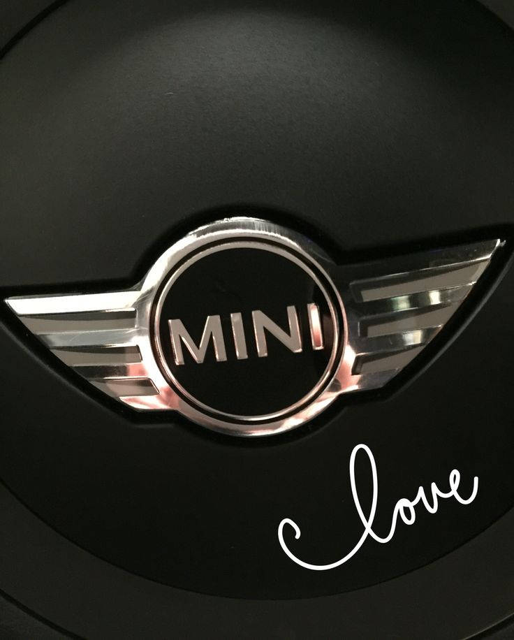 Mini Cooper 桌布 壁紙 — 黑色方向盤上閃亮MINI標誌的特寫，上面有白色草書字體寫著「love」。