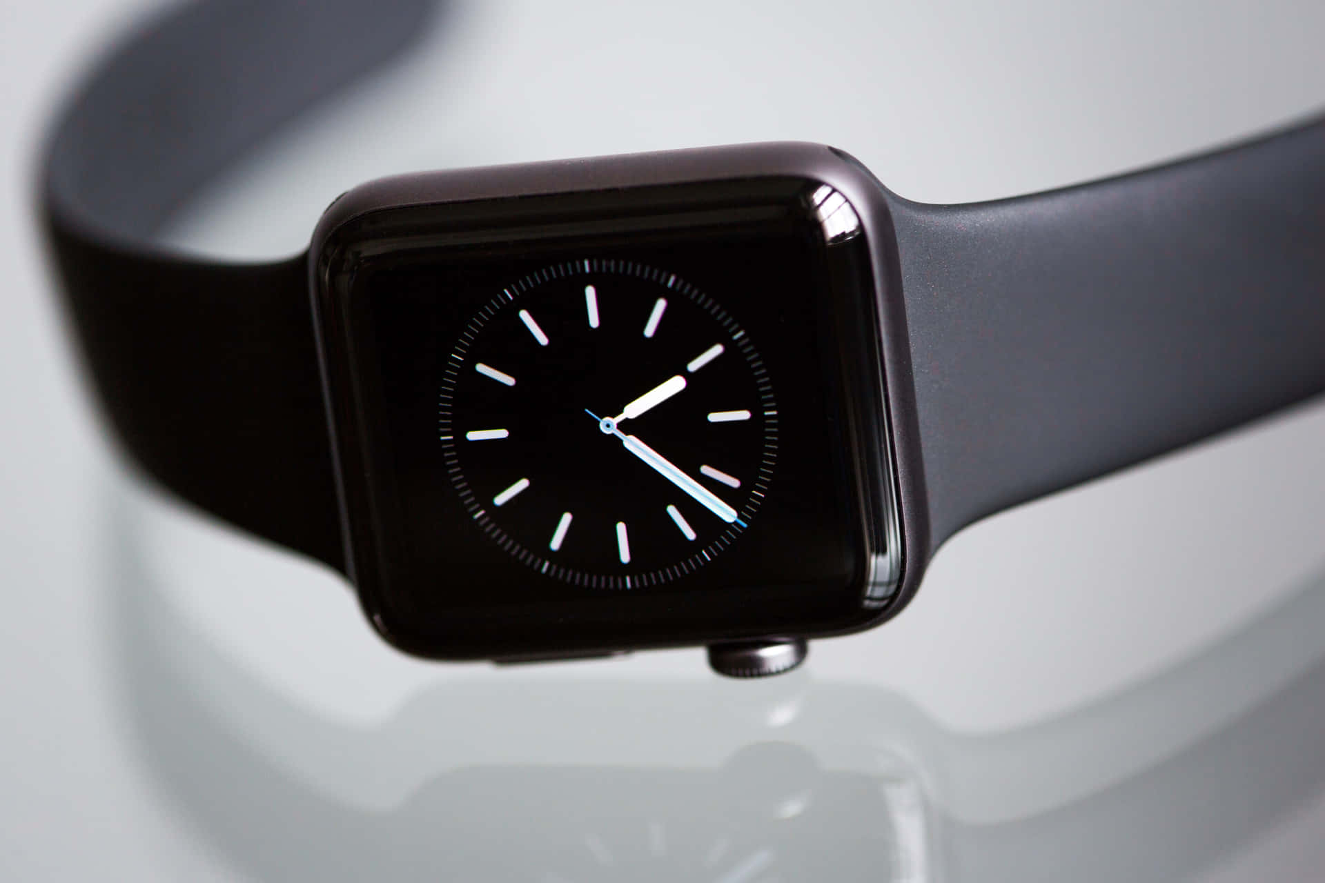 黑色智慧手錶，白色指針，置於反光表面上。 — Apple Watch 動態 壁紙