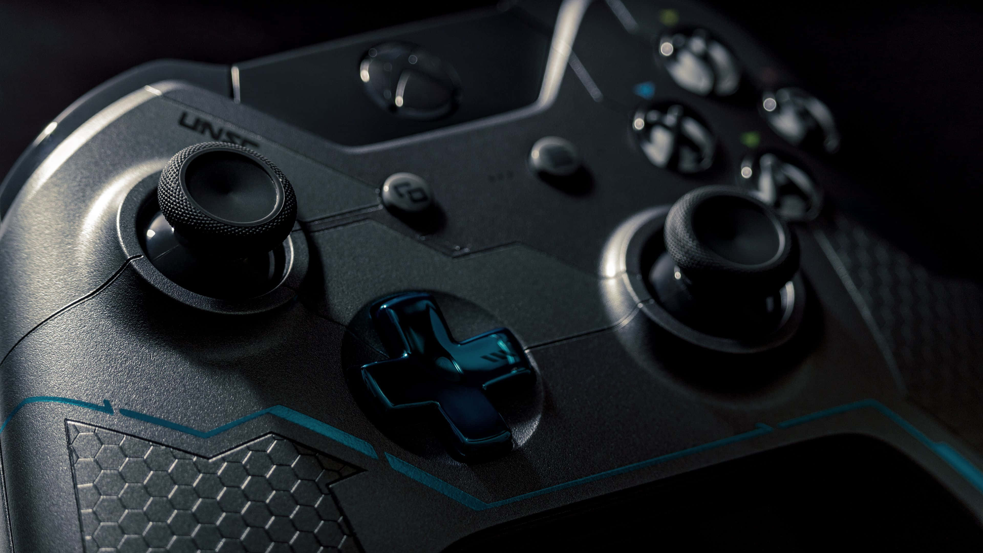 4K Gaming Consoles 桌布 壁紙 — 黑色時尚遊戲控制器特寫，帶有發光藍色點綴和紋理握把，在戲劇性燈光下。