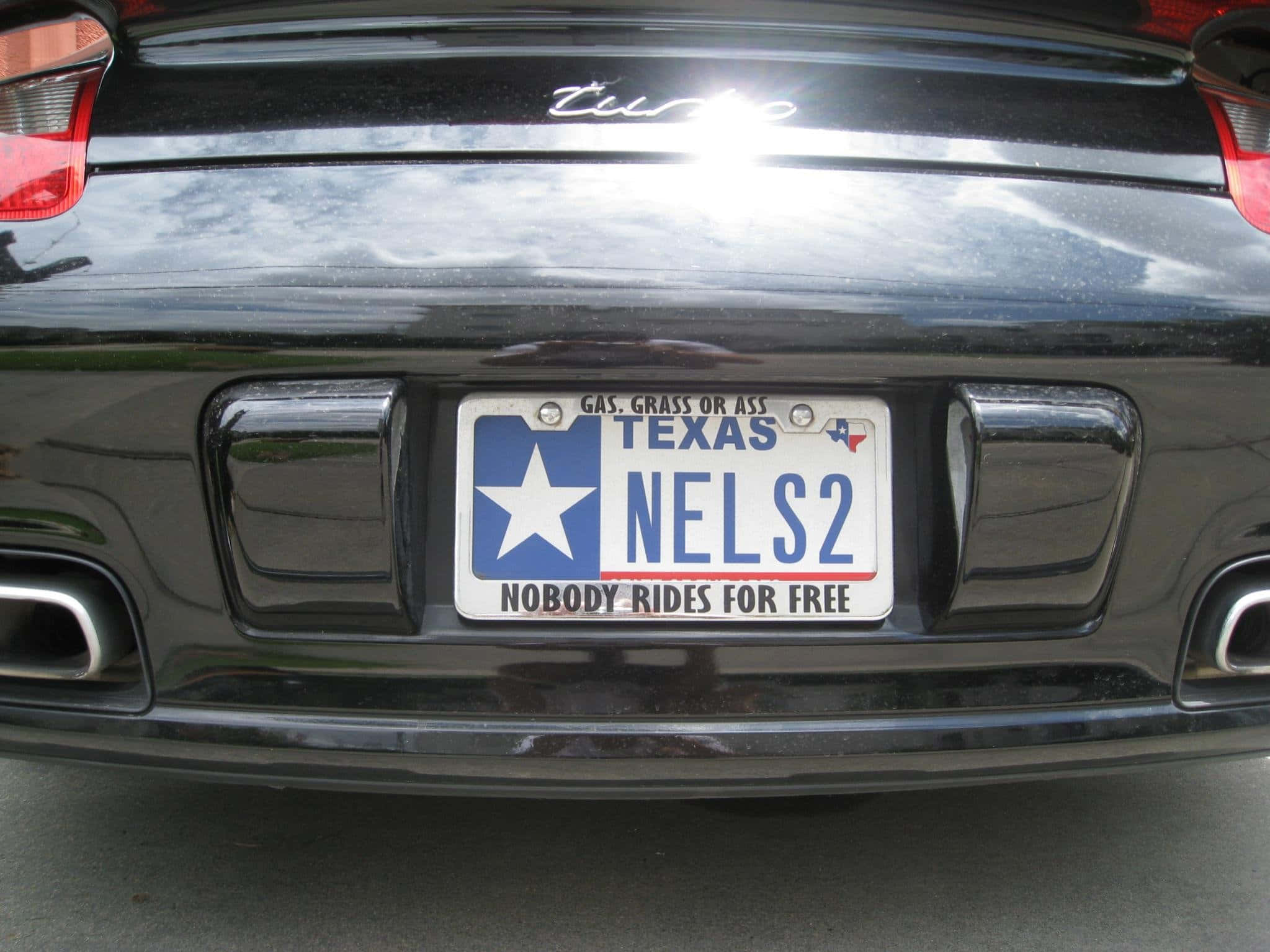 Car License Plate 桌布 壁紙 — 黑色汽車後保險桿的特寫，顯示帶有星星和標語的德克薩斯州車牌。