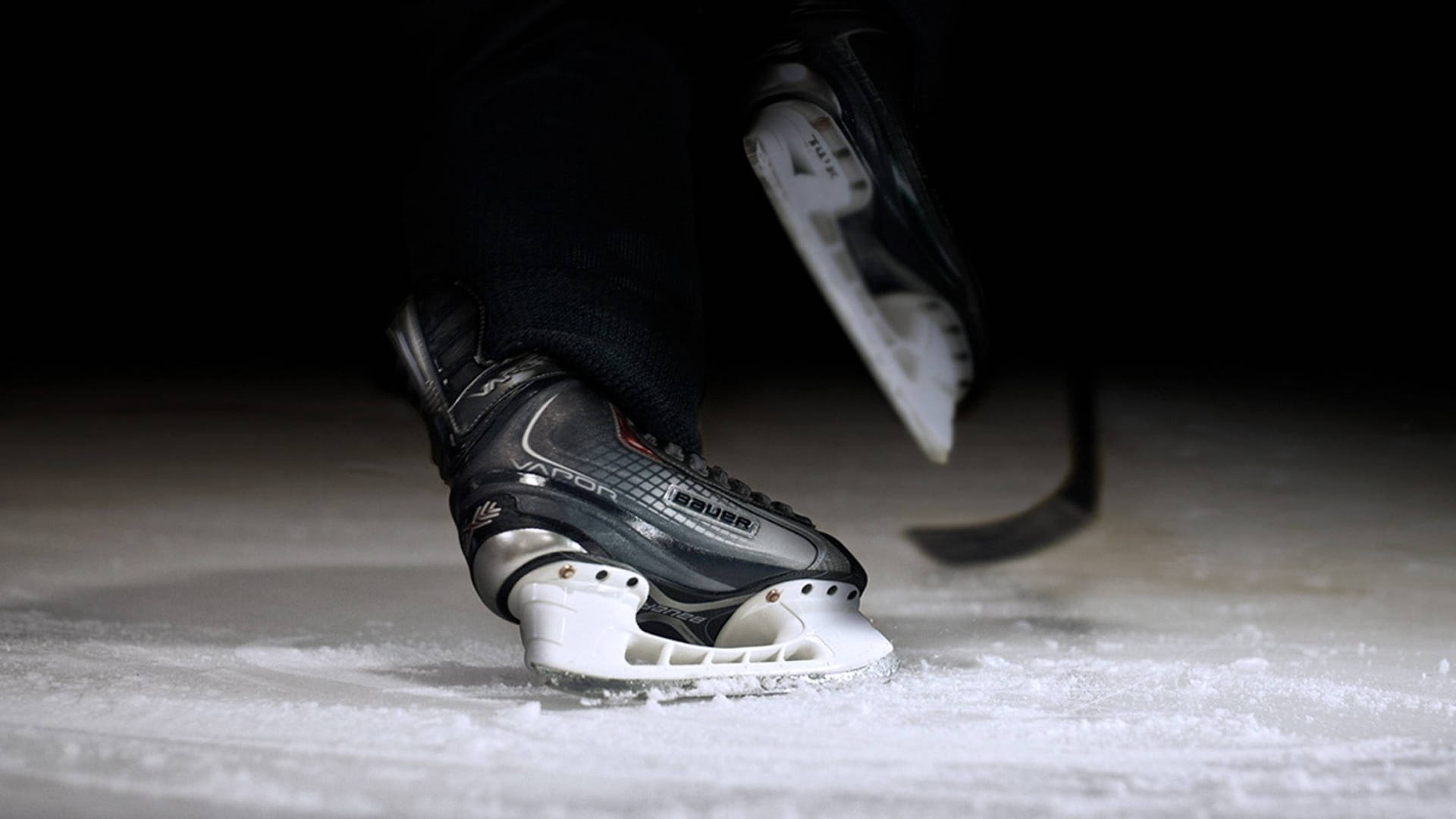 hockey 桌布 壁紙 — 黑色溜冰鞋在紋理冰面上滑行的特寫，背景深色。
