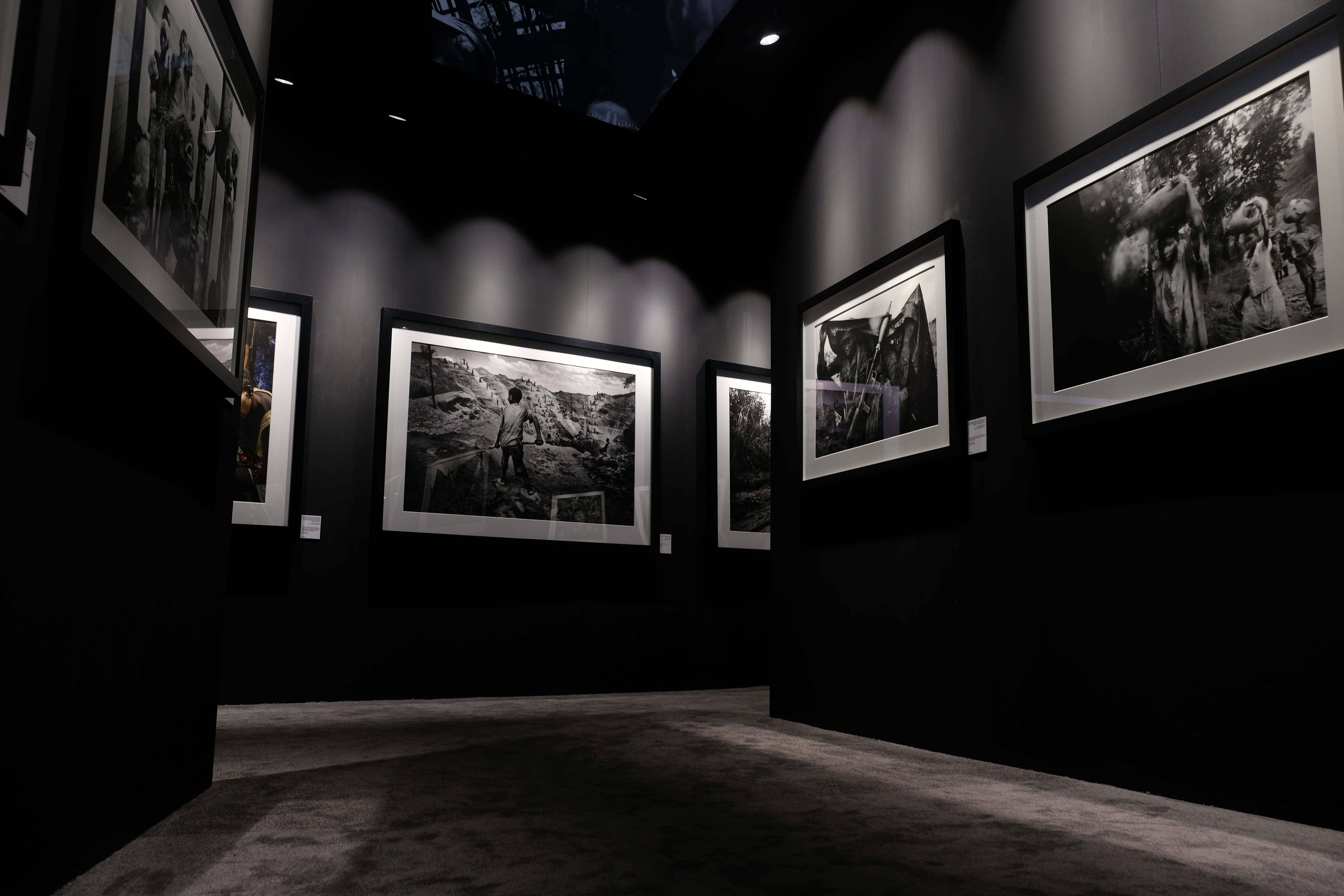 Gallery 桌布 壁紙 — 黑色牆壁上懸掛著時尚相框中的黑白照片，在極簡主義畫廊空間中戲劇性地照亮。