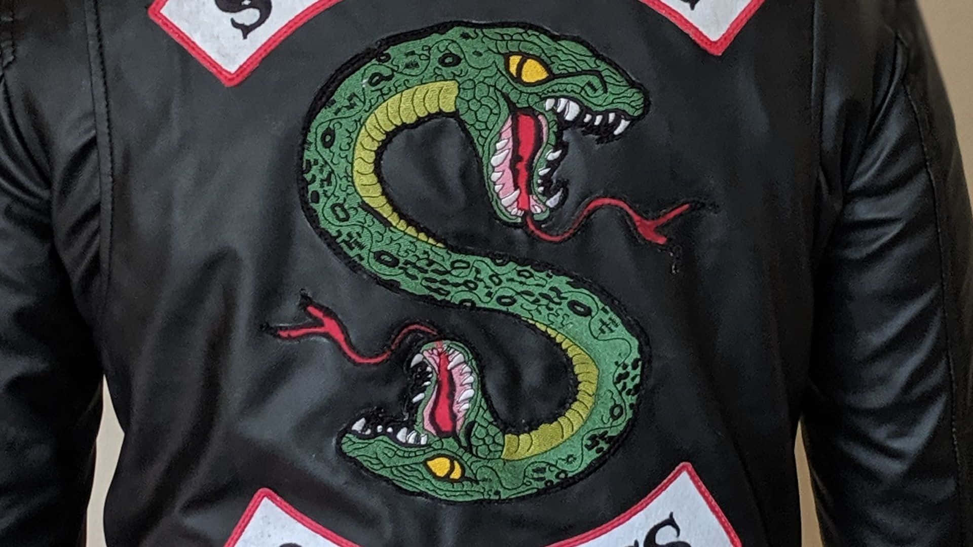 Southside Serpents 桌布 壁紙 — 黑色皮夾克的特寫，上面有鮮綠色刺繡蛇形組成字母S。