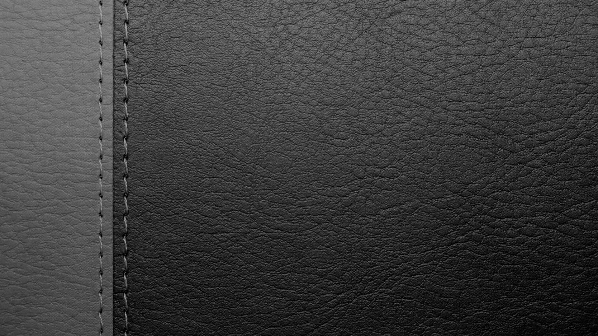 Black Leather 桌布 壁紙 — 黑色皮革特寫，帶有紋理顆粒和對比灰色縫合接縫，分隔兩個面板。