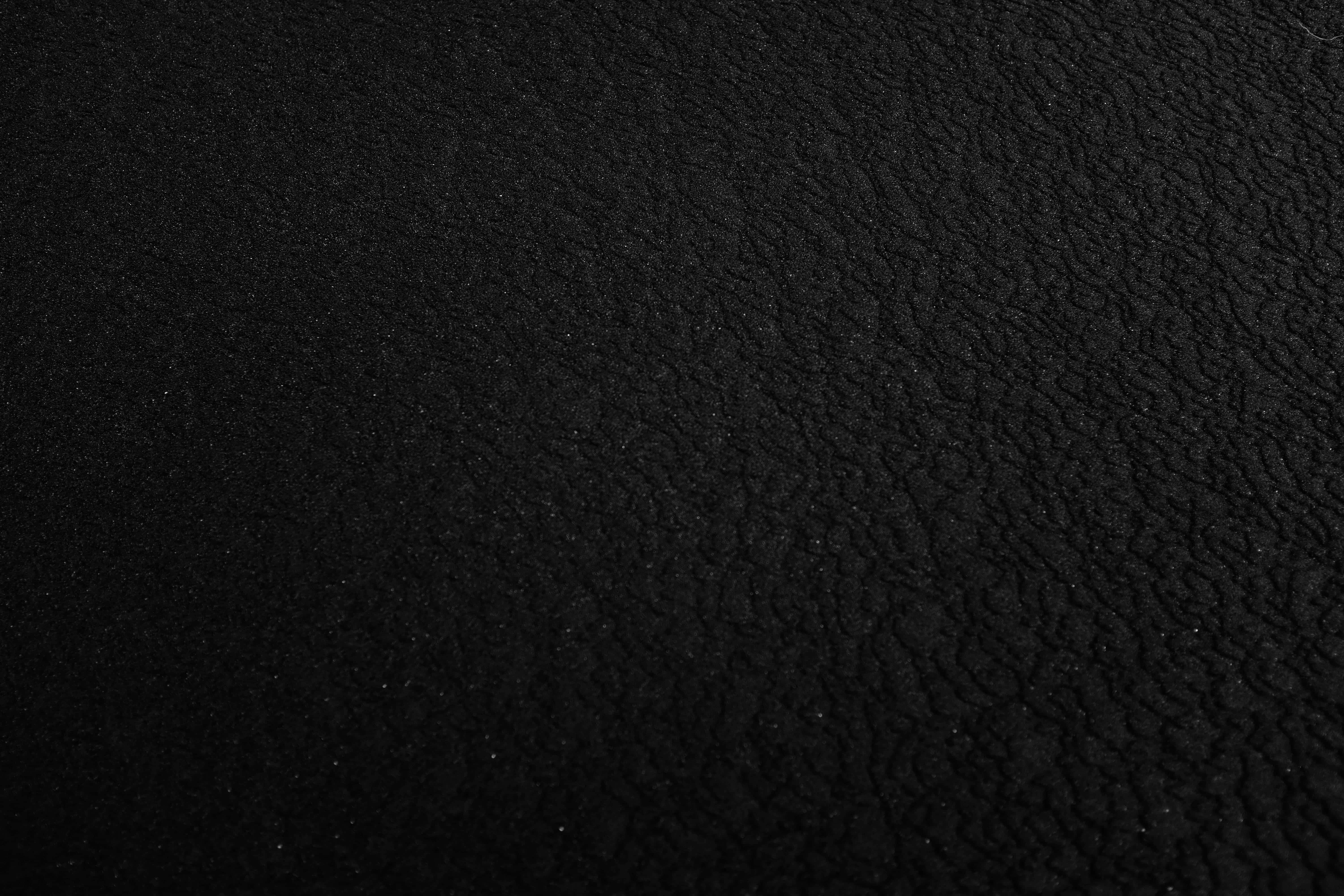 Black Gradient 桌布 壁紙 — 黑色皮革表面的特寫，在柔和光線下帶有細微的紋理和淡淡的斑點。
