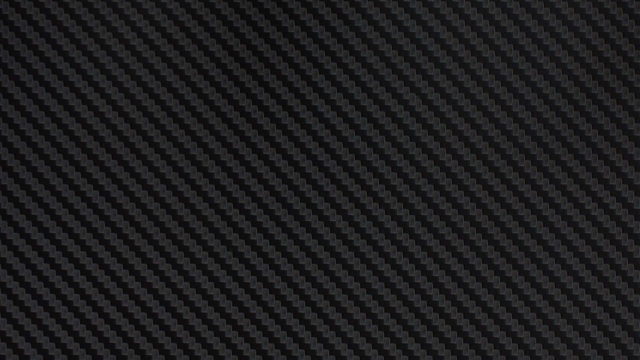 2560x1440 Black 桌布 壁紙 — 黑色碳纖維質感特寫，具有斜紋編織圖案和細微光澤。
