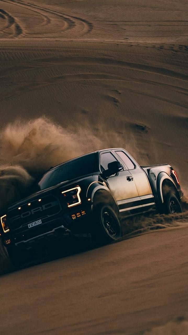 福特 桌布 壁紙 — 黑色福特 F-150 Raptor 在沙漠沙丘上高速飛馳，揚起沙塵，低角度拍攝充滿戲劇性。
