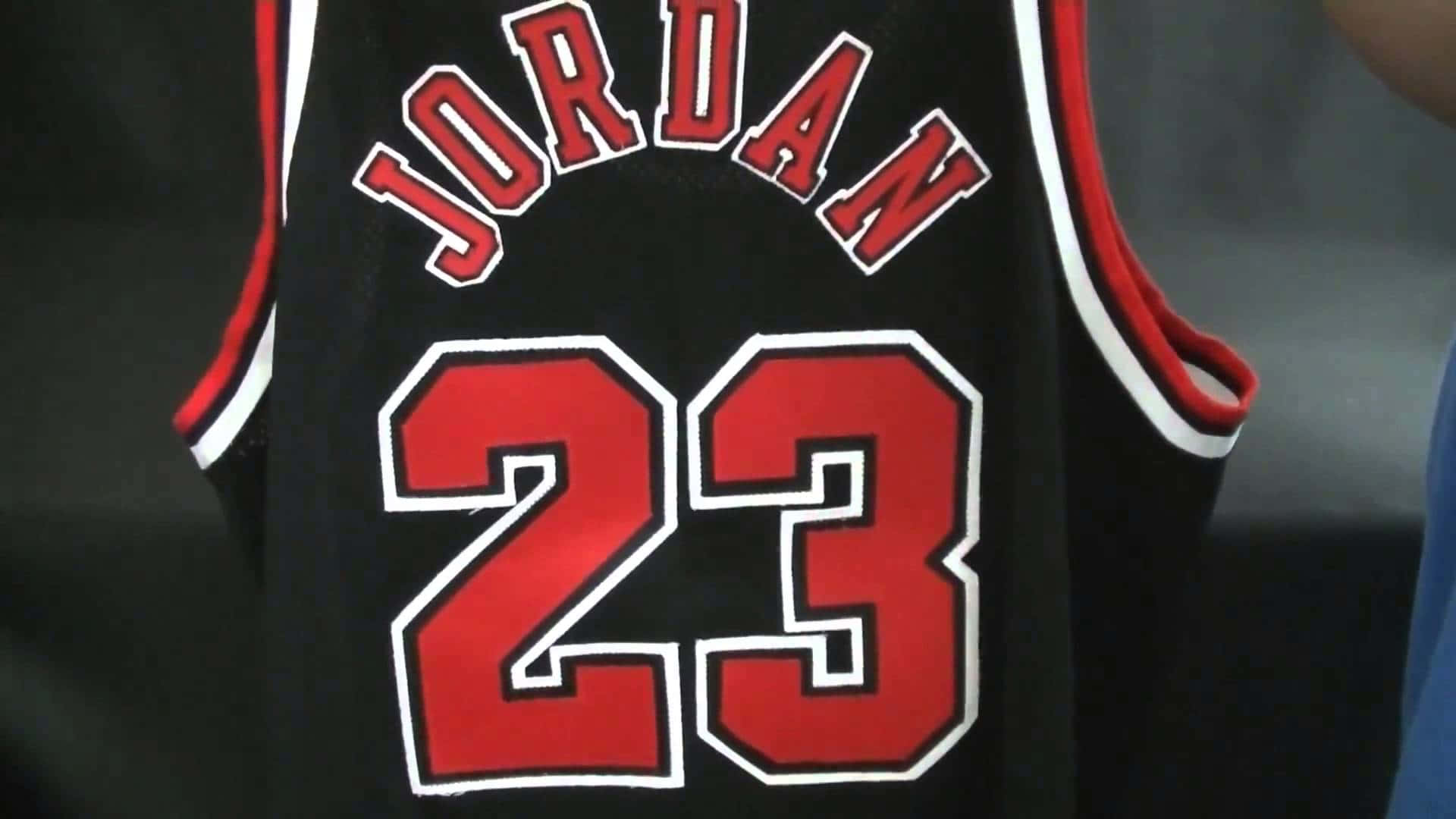桌布 壁紙 — 黑色籃球球衣特寫，帶有紅色和白色的「JORDAN 23」字樣和號碼。
