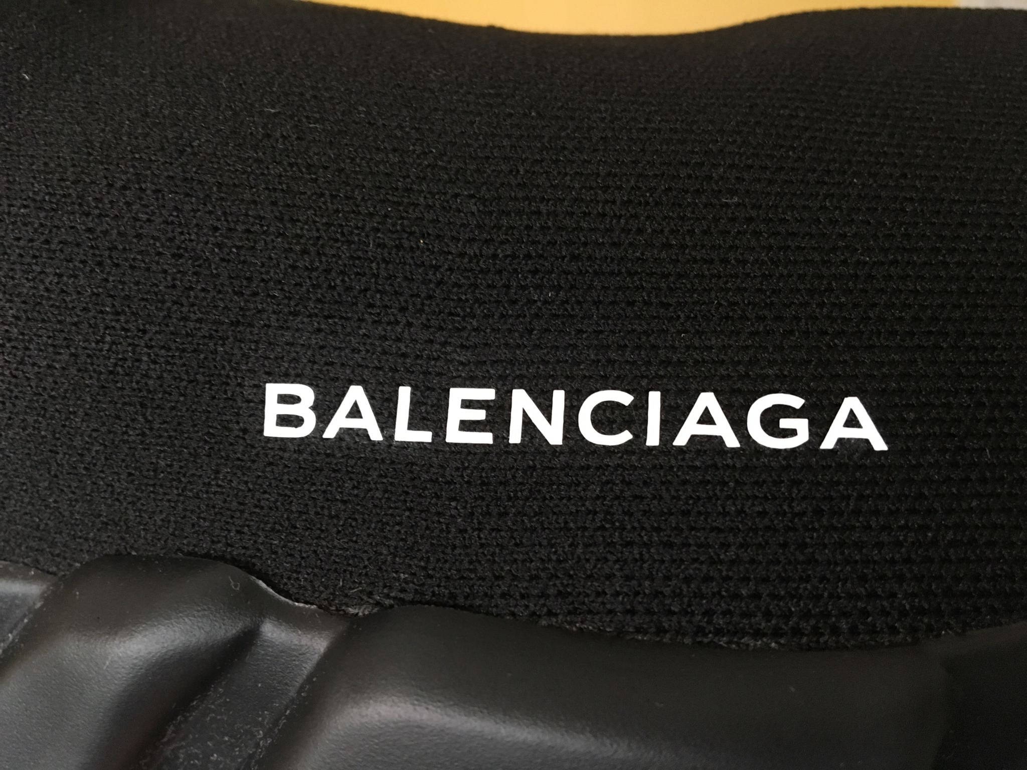 Balenciaga 桌布 壁紙 — 黑色紋理布料特寫，白色 Balenciaga 標誌縫在黑色皮革狀表面上方。