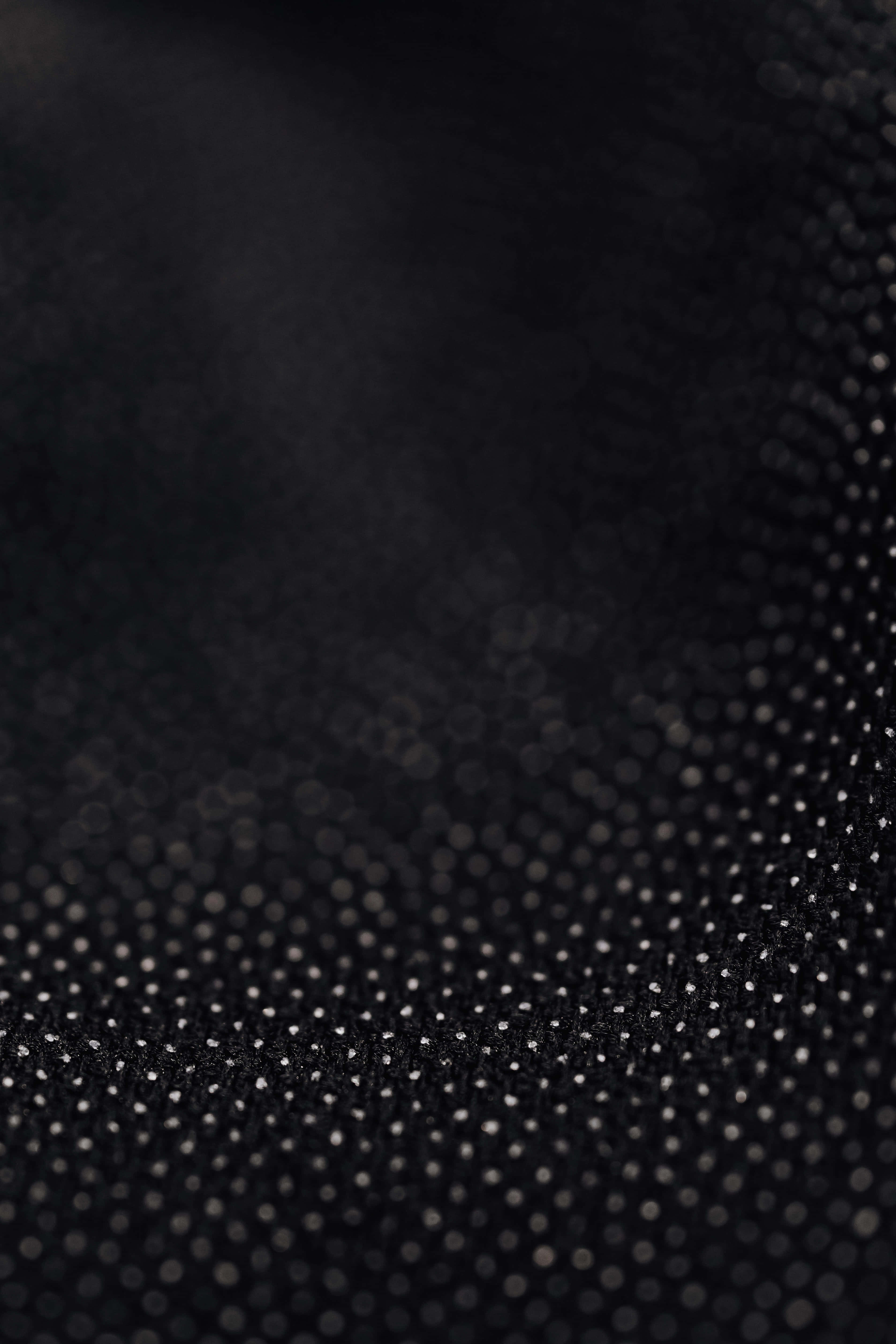 Black And White Dots 桌布 壁紙 — 黑色紋理布料的特寫，散佈著銀色圓點，形成微妙的閃爍圖案。