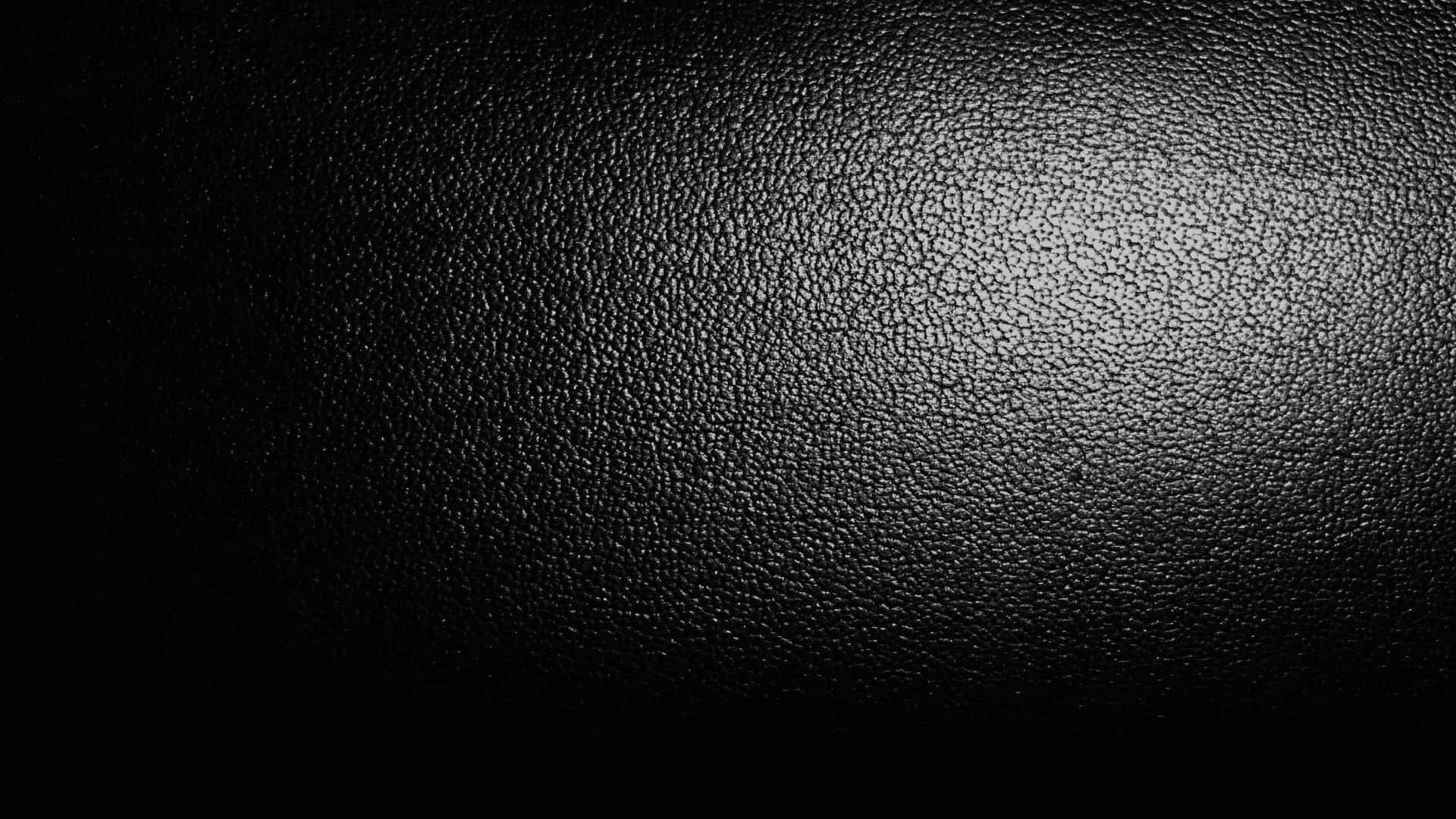 Dark Textured 桌布 壁紙 — 黑色紋理皮革表面的特寫，帶有從中心柔和的漸變照明。