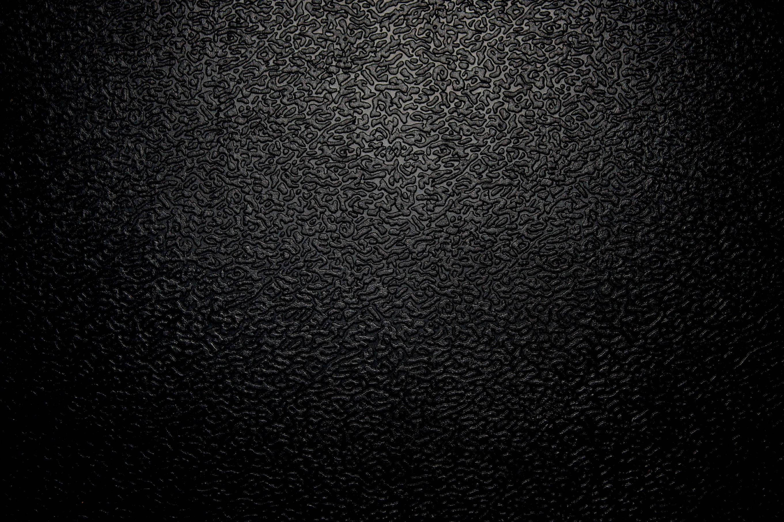 texture 桌布 壁紙 — 黑色紋理表面的特寫，帶有微妙的燈光漸變，突出其複雜的壓花圖案。