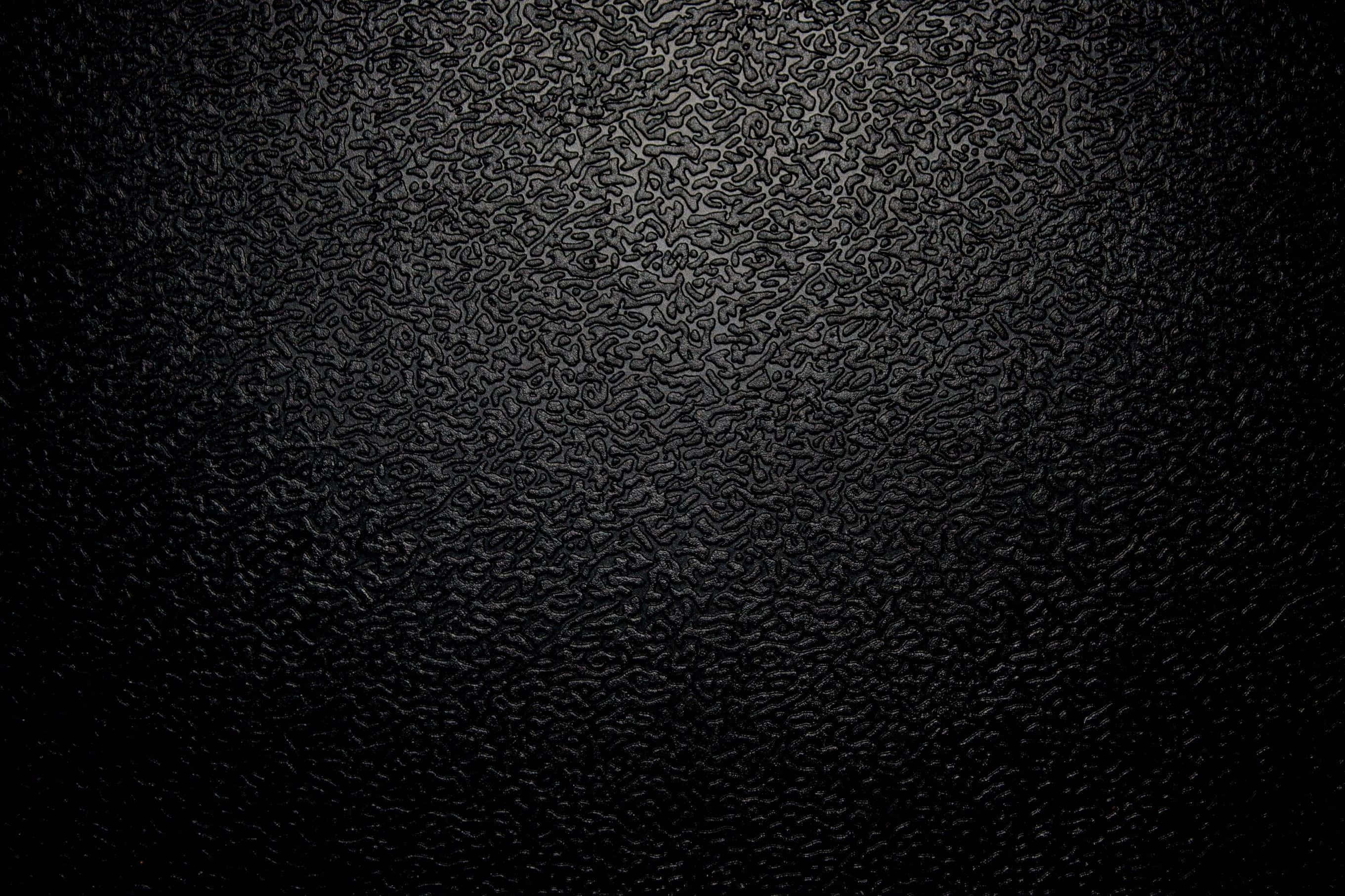texture 桌布 壁紙 — 黑色紋理表面的特寫，帶有微妙的燈光漸變，突出其複雜的壓花圖案。