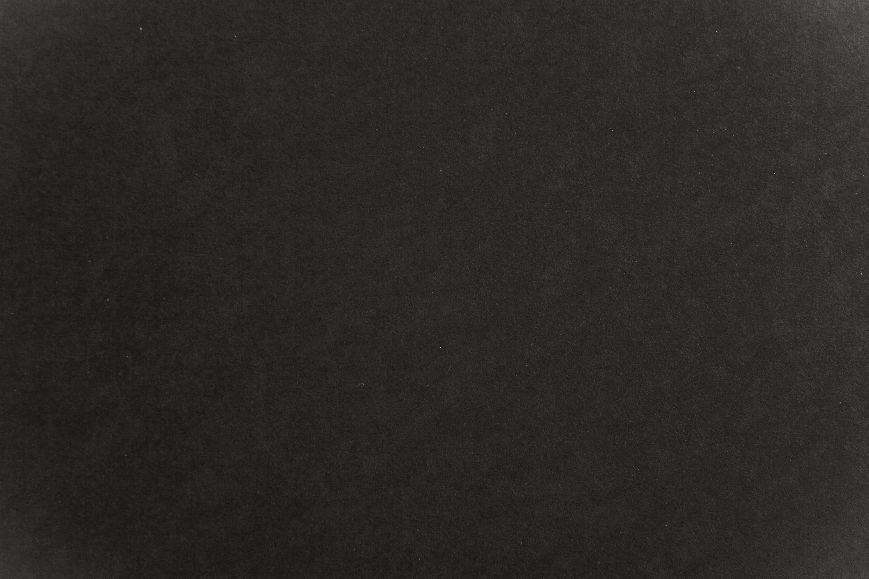 Black Paper Texture 桌布 壁紙 — 黑色紋理表面的特寫，整個畫面帶有細微的顆粒和淡淡的斑點。