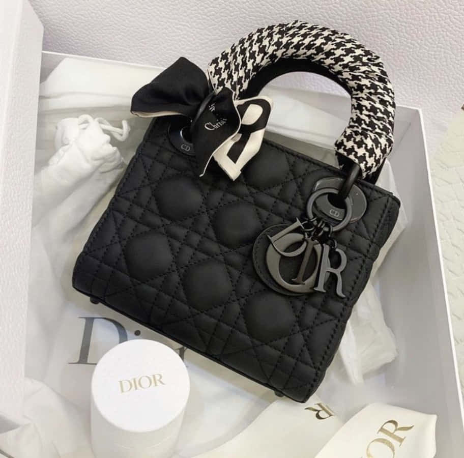 Dior 動態 桌布 壁紙 — 黑色絎縫Dior Lady Dior手提包，配有千鳥格手柄和蝴蝶結，放置在帶有Dior配件的白色盒子中。