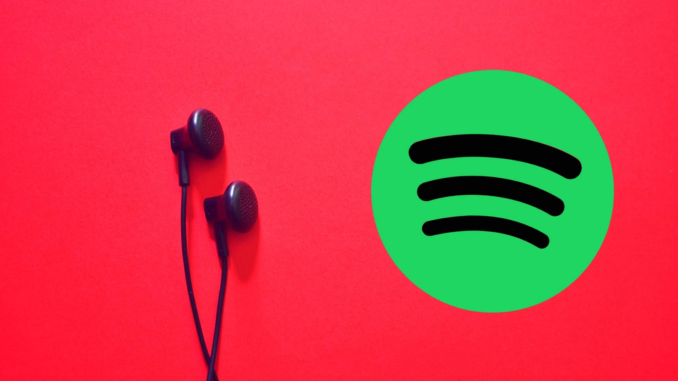 Spotify 桌布 壁紙 — 黑色耳機放在鮮紅色背景上的綠色Spotify標誌旁邊。